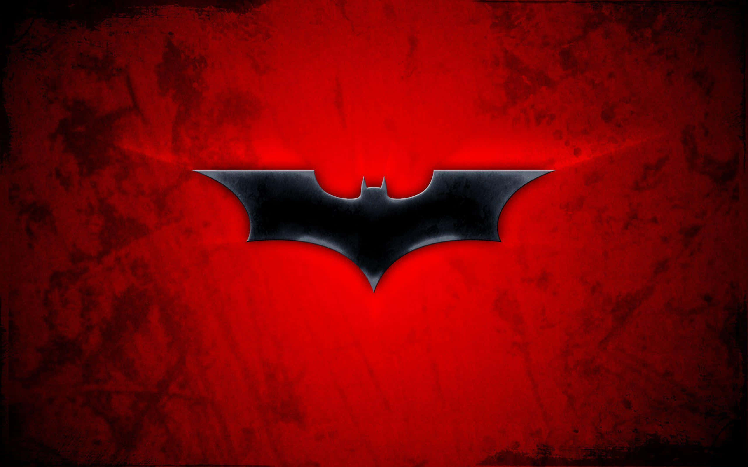 Batman Under The Red Hood 桌布 壁紙 — 一個時尚的黑色蝙蝠標誌在帶有紋理的深紅色背景上發光，背後散發出微妙的光線。