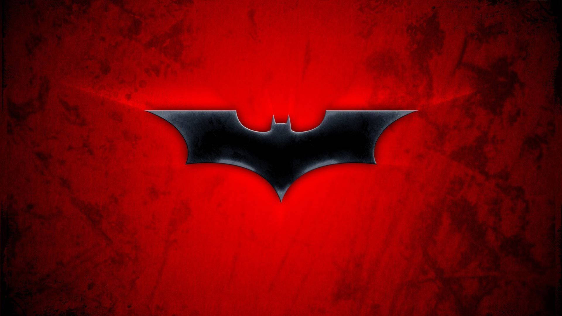 Batman Logo 桌布 壁紙 — 一個時尚的黑色蝙蝠標誌在帶有紋理的深紅色背景上發光，背後散發出微妙的光線。