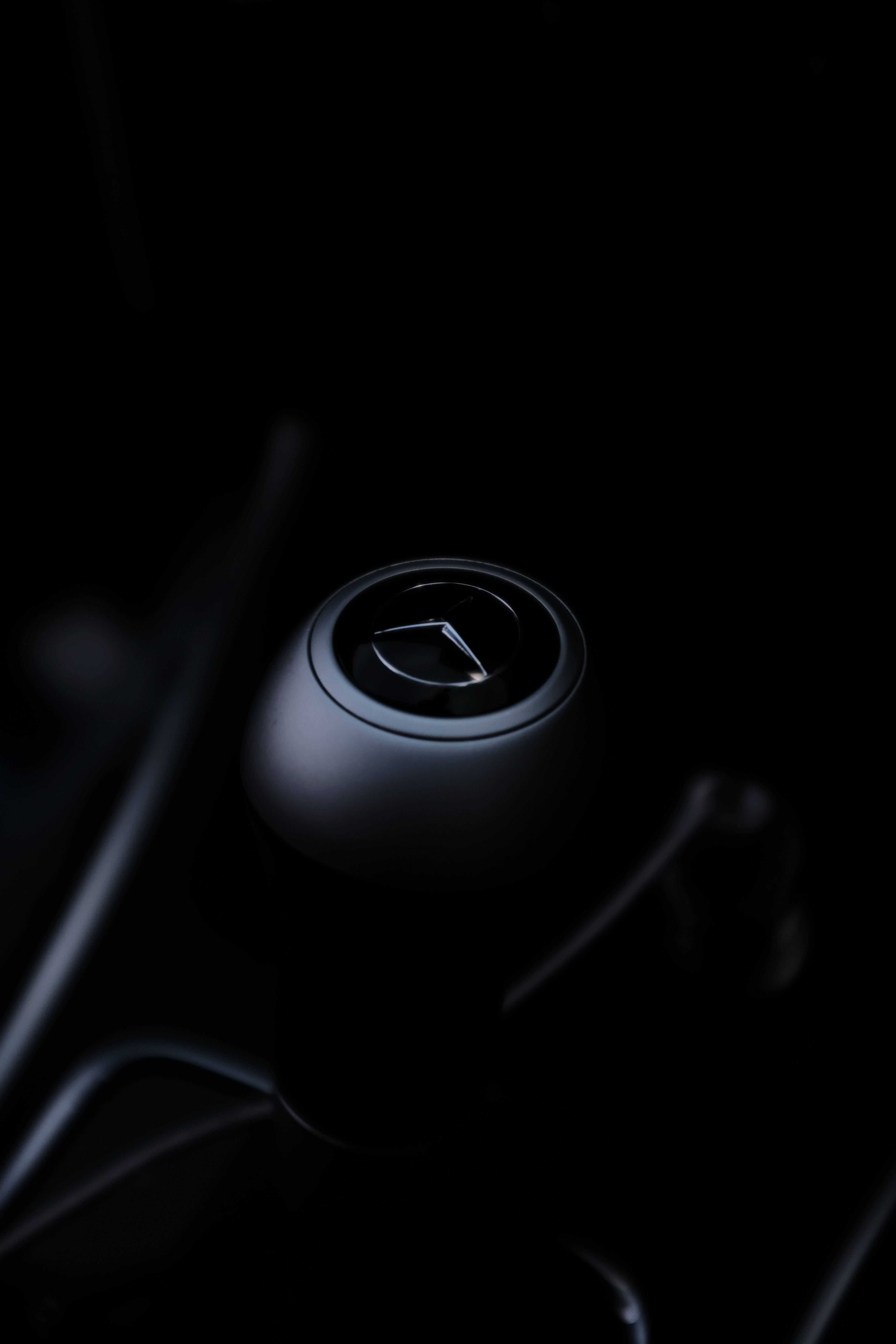 Mercedes 桌布 壁紙 — 一個時尚的黑色賓士排檔桿，在昏暗的車廂內被柔和光線照亮。