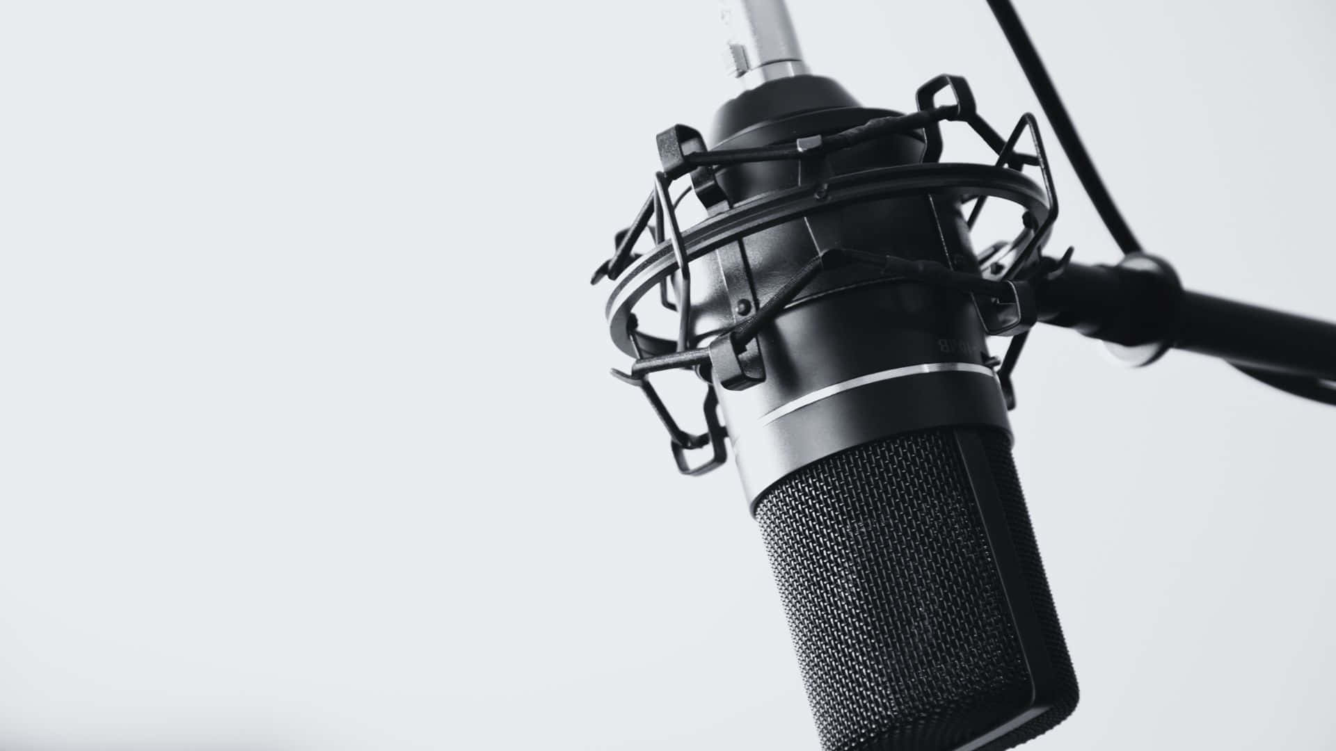 Black And White Music 桌布 壁紙 — 一個時尚的黑色錄音室麥克風，帶有保護罩，懸掛在極簡的白色背景上。