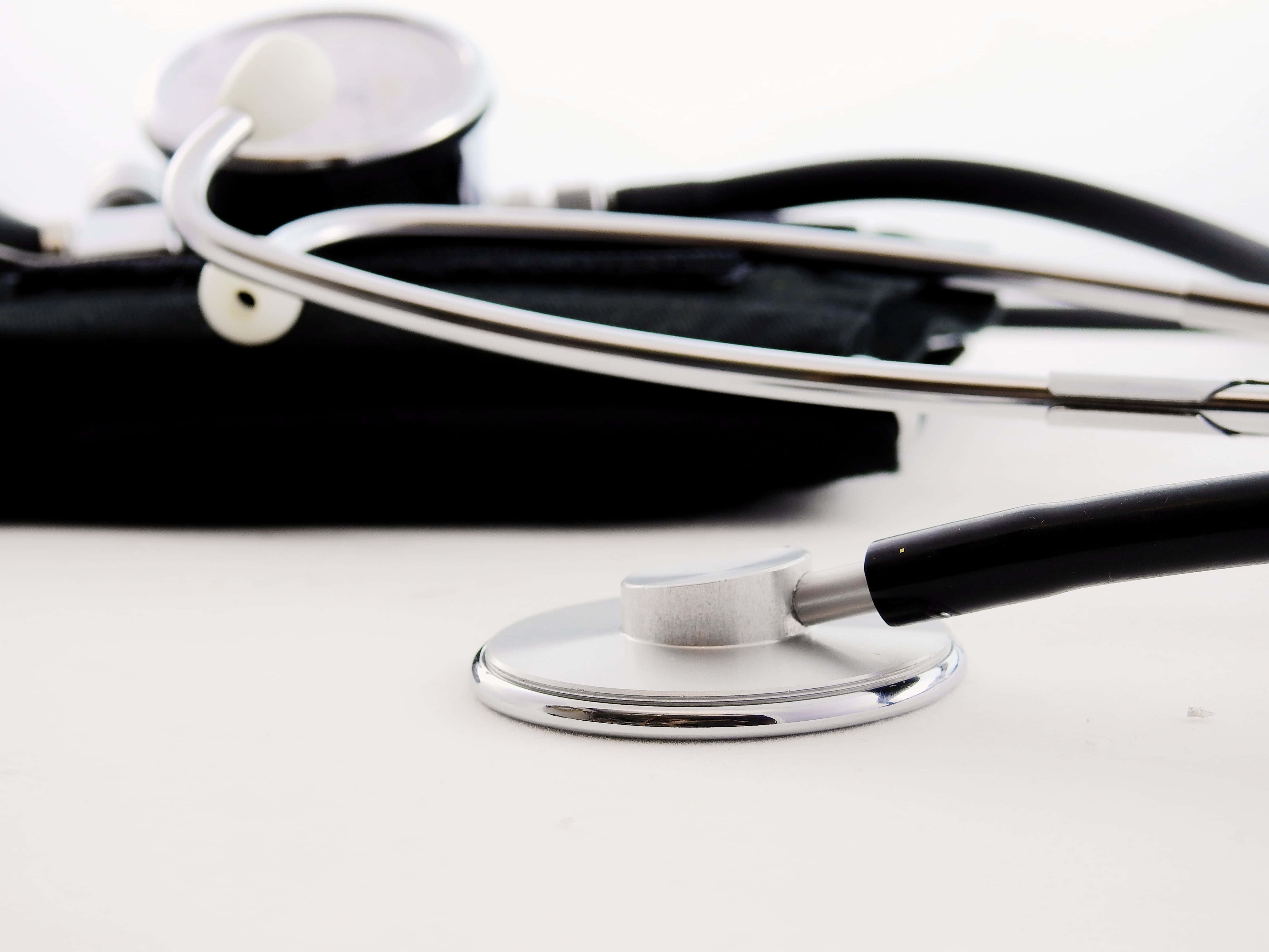 Stethoscope 桌布 壁紙 — 一個時尚銀色聽診器的特寫，放在白色表面上，後面有一個黑色盒子處於柔和焦點。