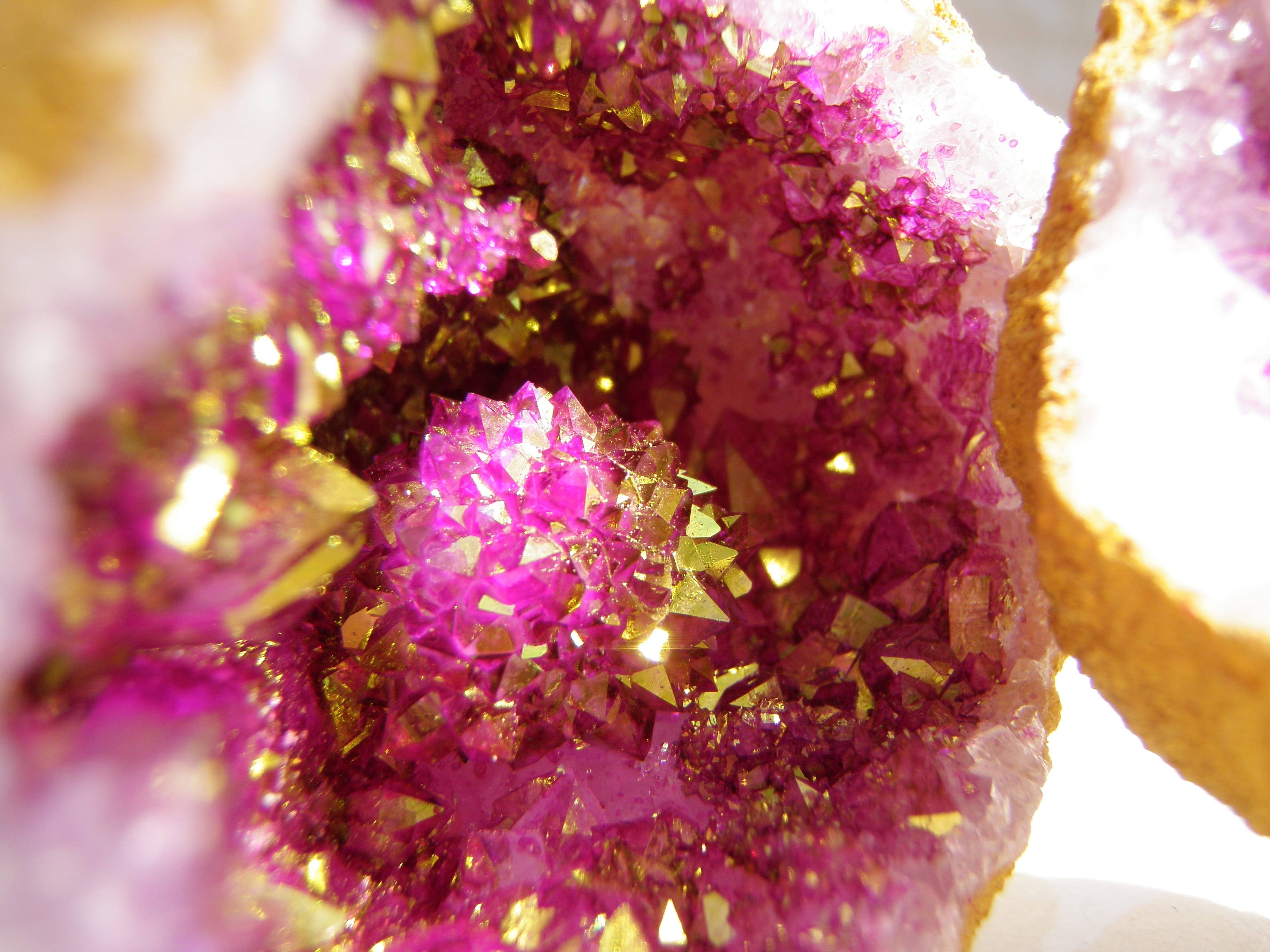 Amethyst 桌布 壁紙 — 一個晶洞的微距特寫，展現出在強光下閃耀的洋紅色和金色晶體。
