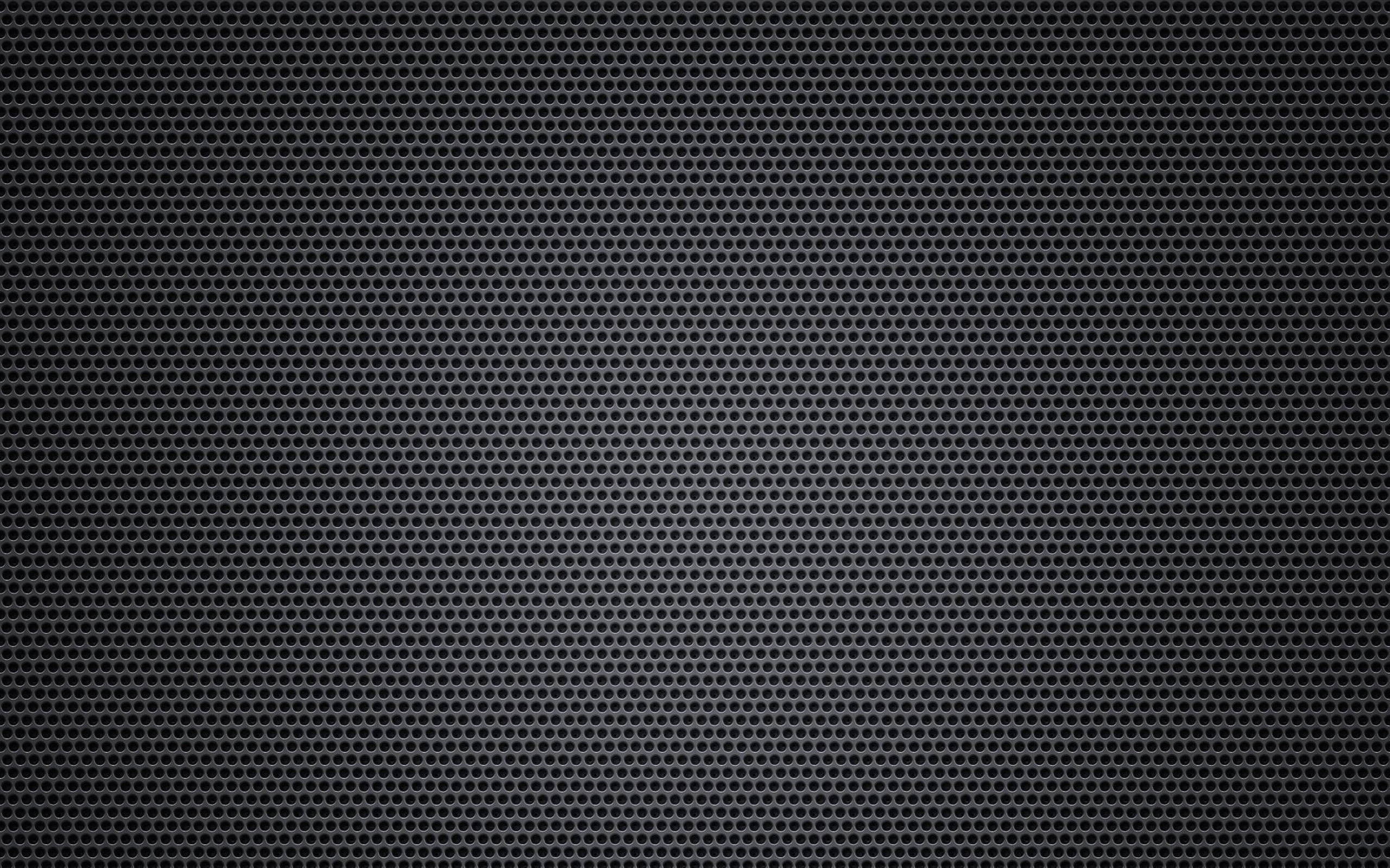 black and white aesthetic grid 桌布 壁紙 — 一個暗色穿孔金屬格柵的特寫，帶有均勻分佈的圓形孔洞，形成有紋理的工業圖案。