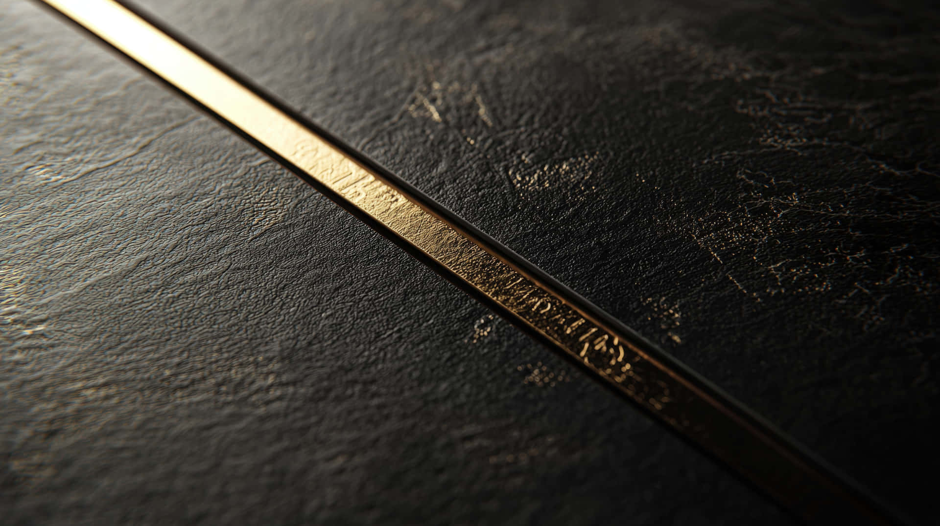 Black Leather Texture with Gold Metallic Detail 壁紙 — 一個暗色紋理表面的特寫，帶有反射光線的對角金色條紋。