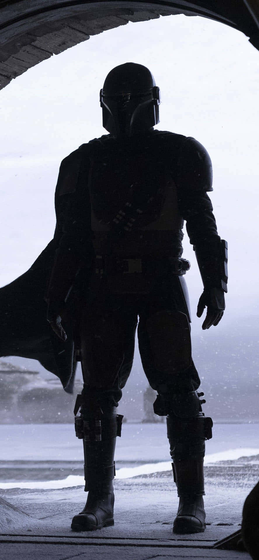 Mandalorian Pc 桌布 壁紙 — 一個曼達洛戰士以剪影形式站在雪景前，由彎曲的門口框住。