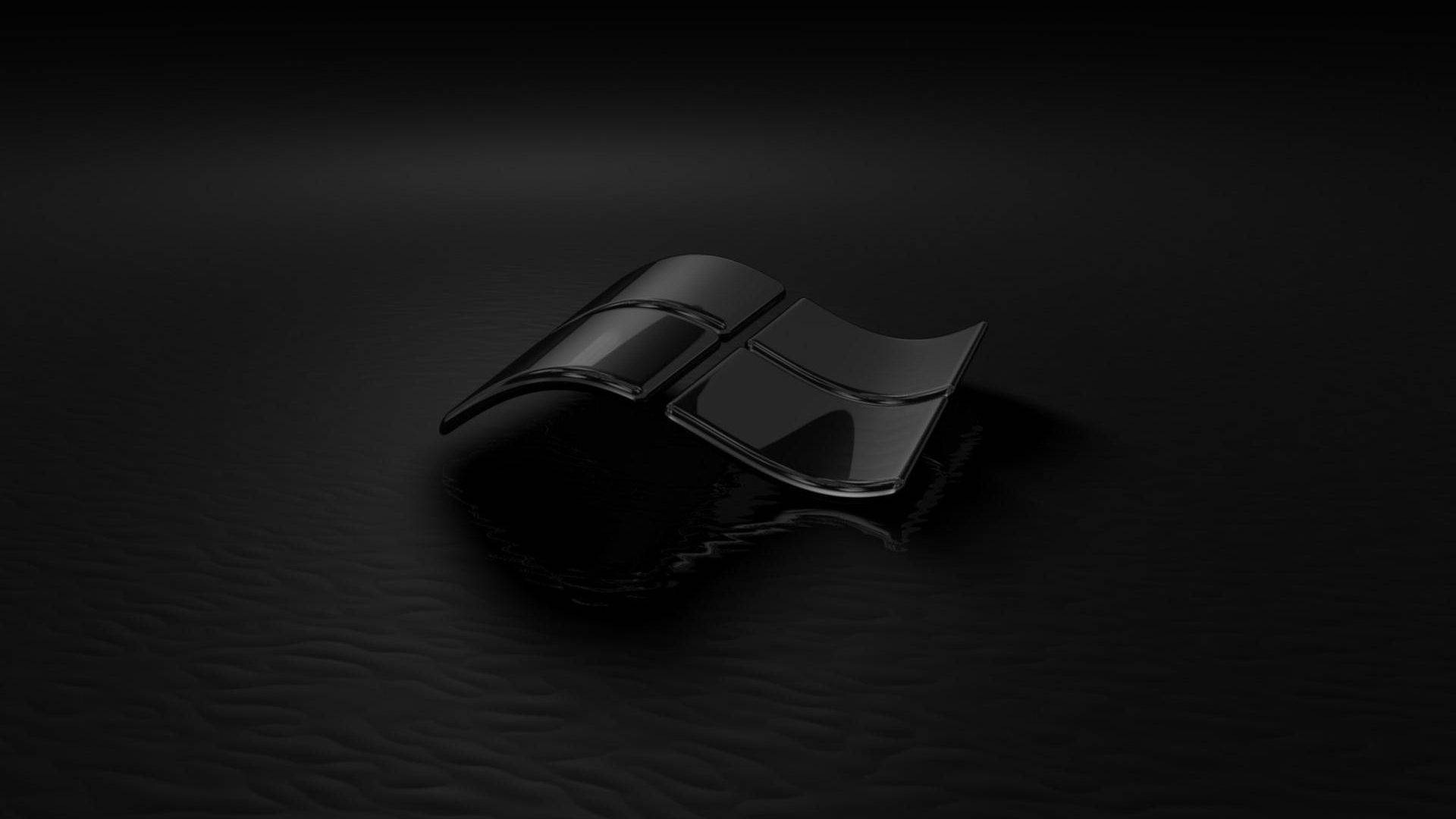 3D 桌布 壁紙 — 一個有光澤的黑色Windows標誌放置在帶有紋理的深色表面上，在戲劇性的聚光燈下。