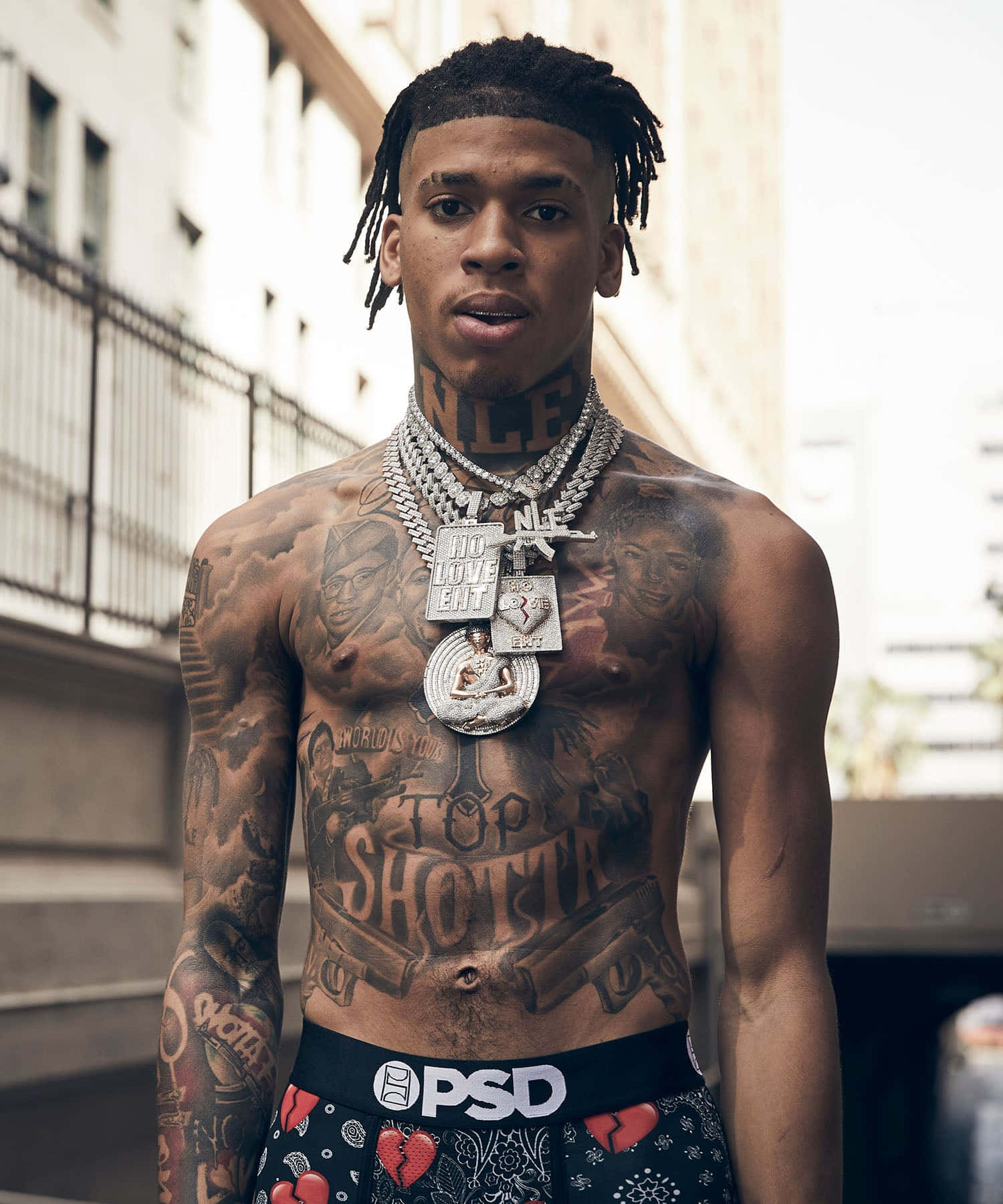 有刺青、戴著鏈子和圖案內褲的男人在都市小巷中。 — NLE Choppa GIF 壁紙