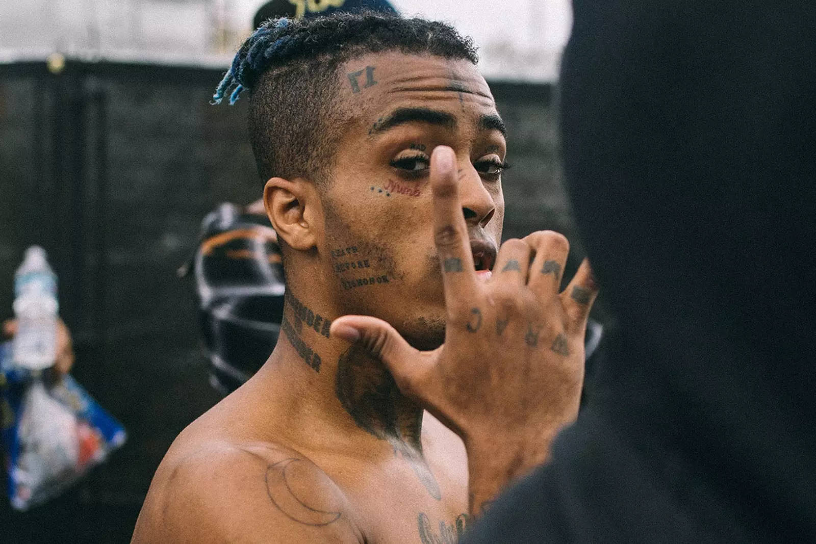 xxxtentacion 電腦 桌布 壁紙 — 一個有刺青、藍色辮子頭的男人，一邊做手勢，一邊專注地看著鏡頭。
