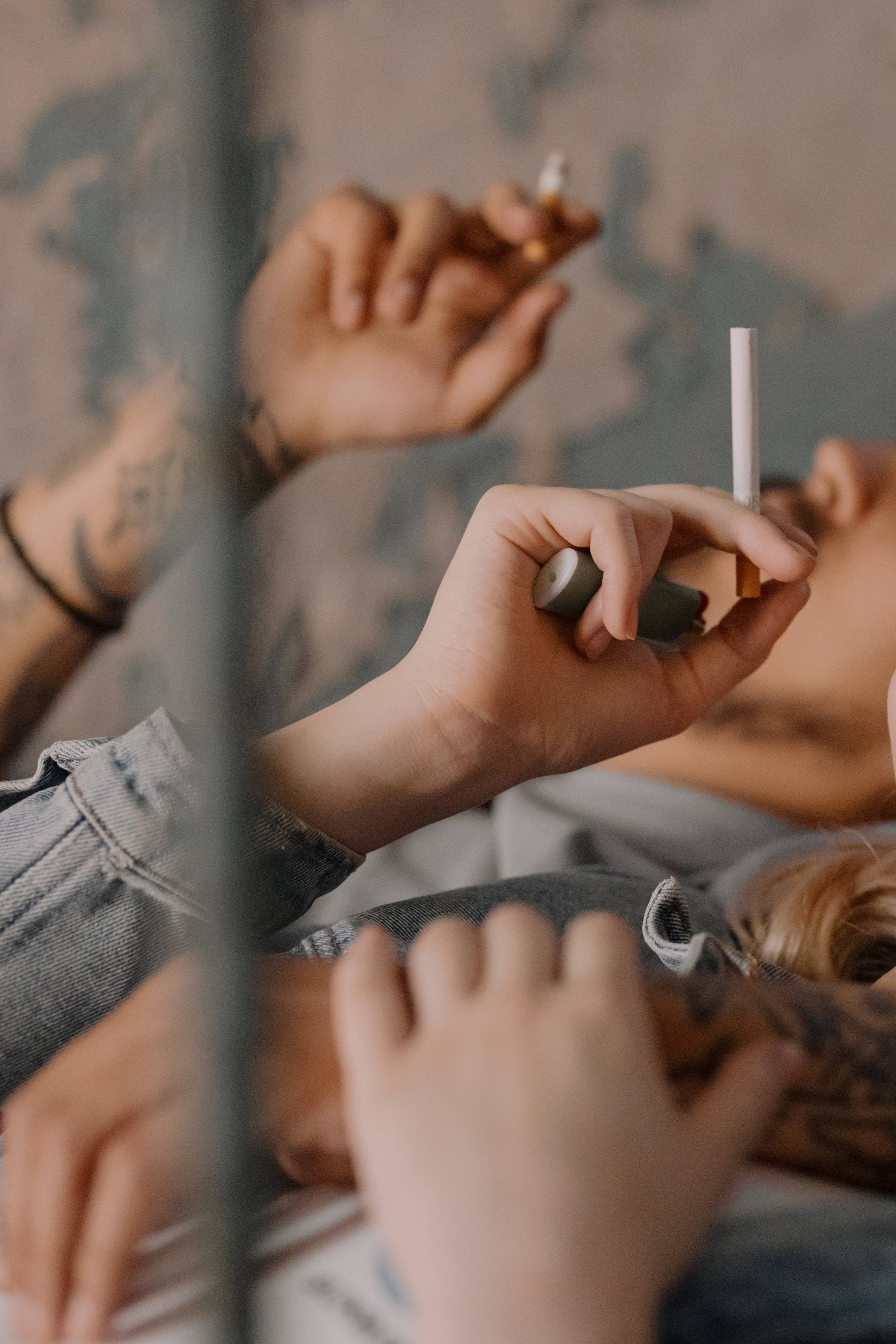 Couple Hands 桌布 壁紙 — 一個有刺青的人躺著吸煙，透過玻璃屏障觀看，色調柔和低沉。