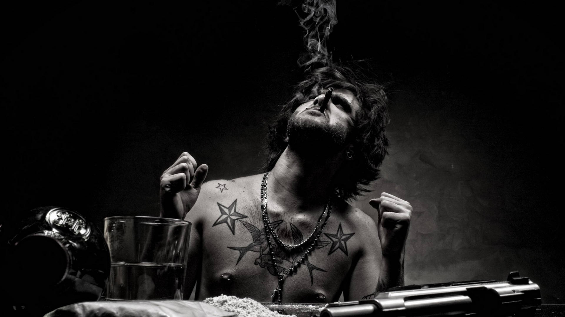 Tattoo 桌布 壁紙 — 一個有刺青的男人在昏暗、陰鬱的黑白場景中，手持香煙向上呼出煙霧。