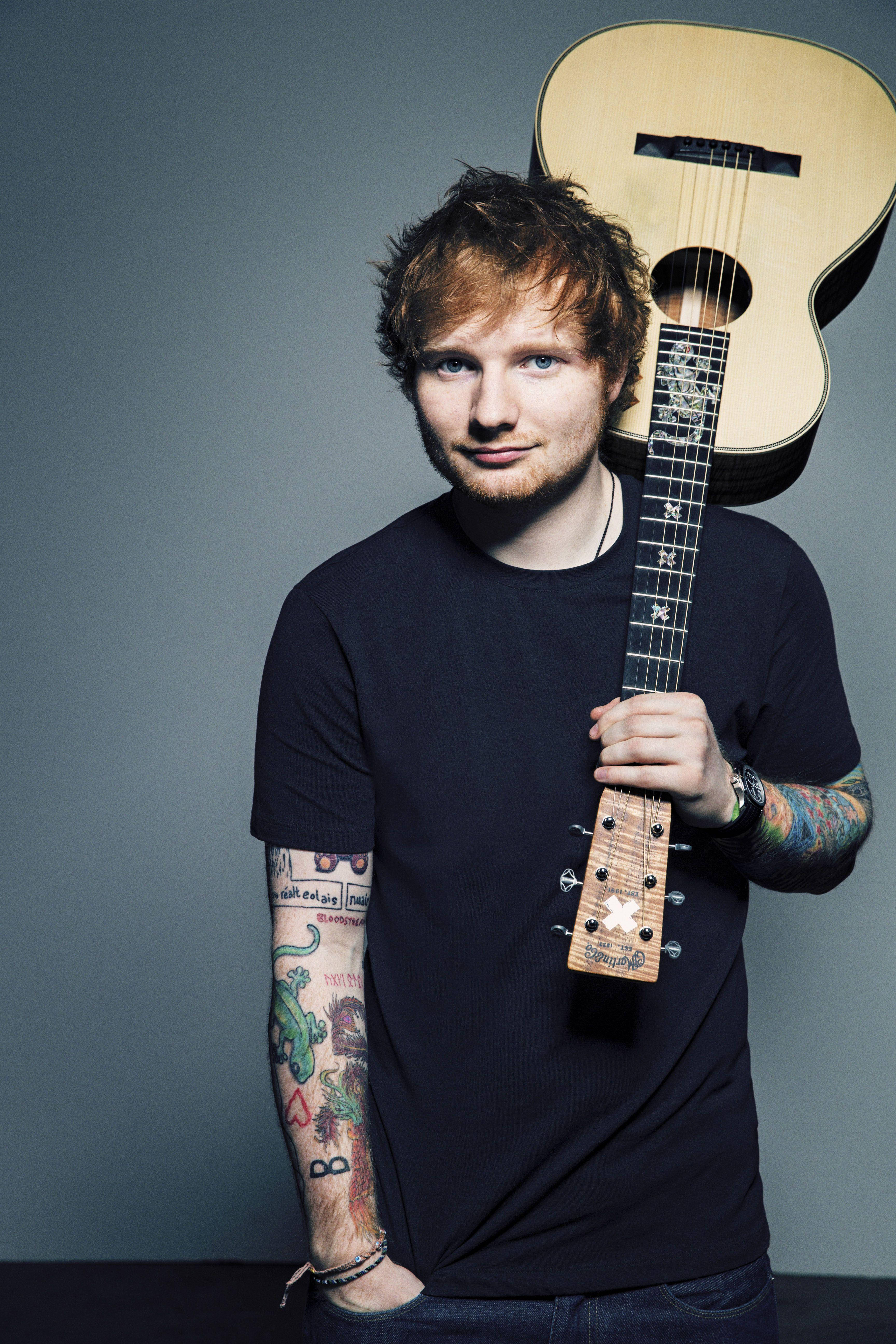 Ed Sheeran 桌布 壁紙 — 一個有刺青的男人在純灰色背景前拿著木吉他的工作室肖像。
