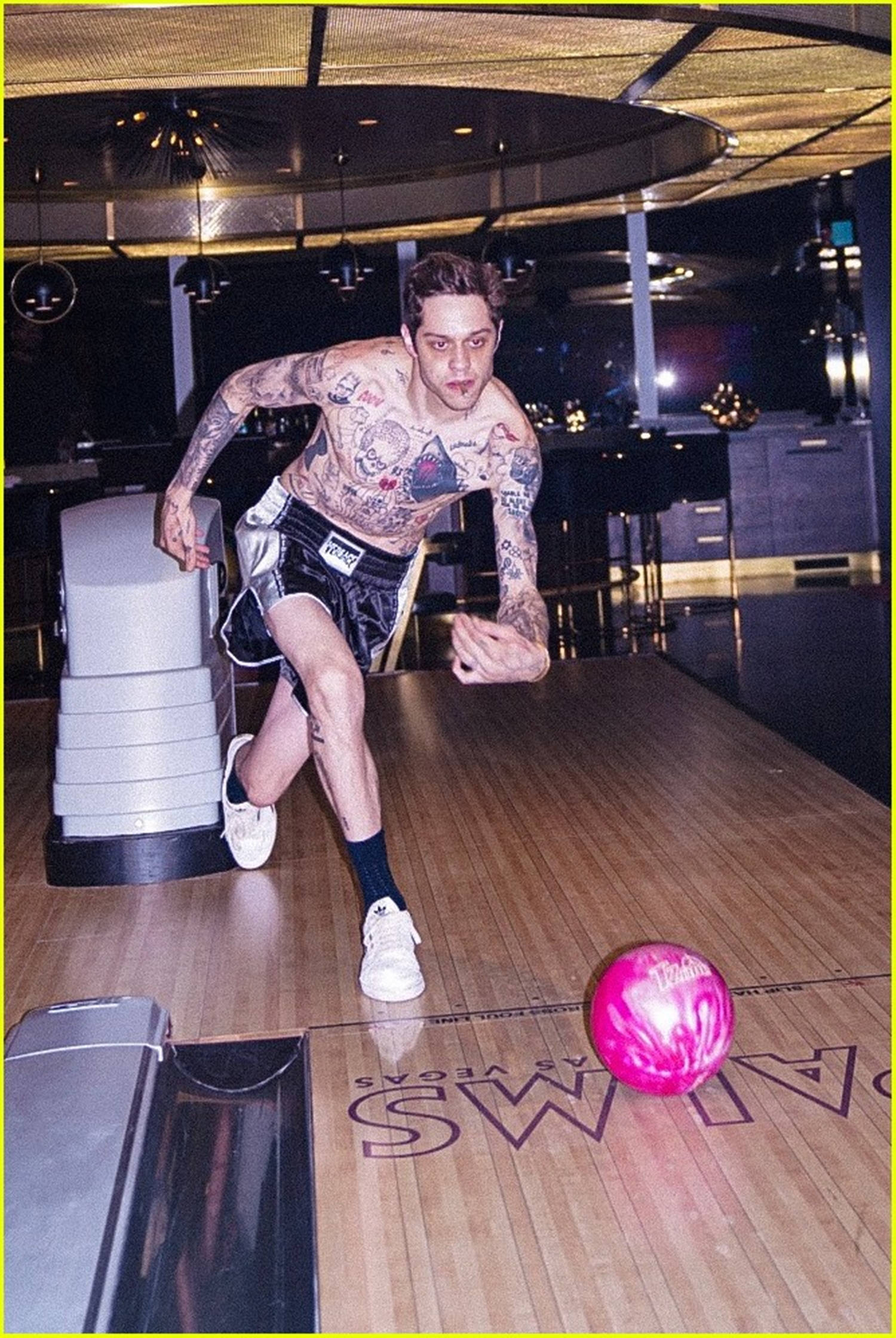 Bowling 桌布 壁紙 — 一個有刺青的男人穿著拳擊短褲，在夜晚的維加斯球道上滾動一個亮粉色的球。
