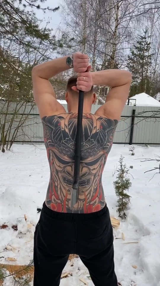 Tattoo 桌布 壁紙 — 一個有刺青的男人站在戶外雪地中，雙手將一根長長的黑色桿子舉過頭頂。