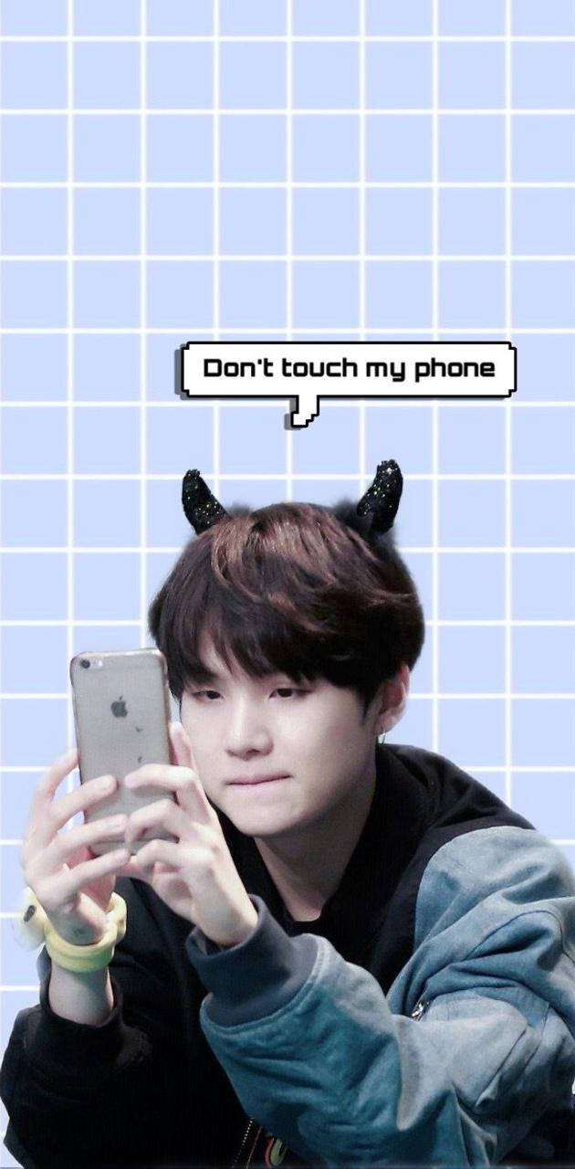 BTS 鎖定螢幕 桌布 壁紙 — 一個有惡魔角的年輕男子，在淺藍色網格背景前防禦性地拿著手機，對話框寫著『不要碰我的手機』。