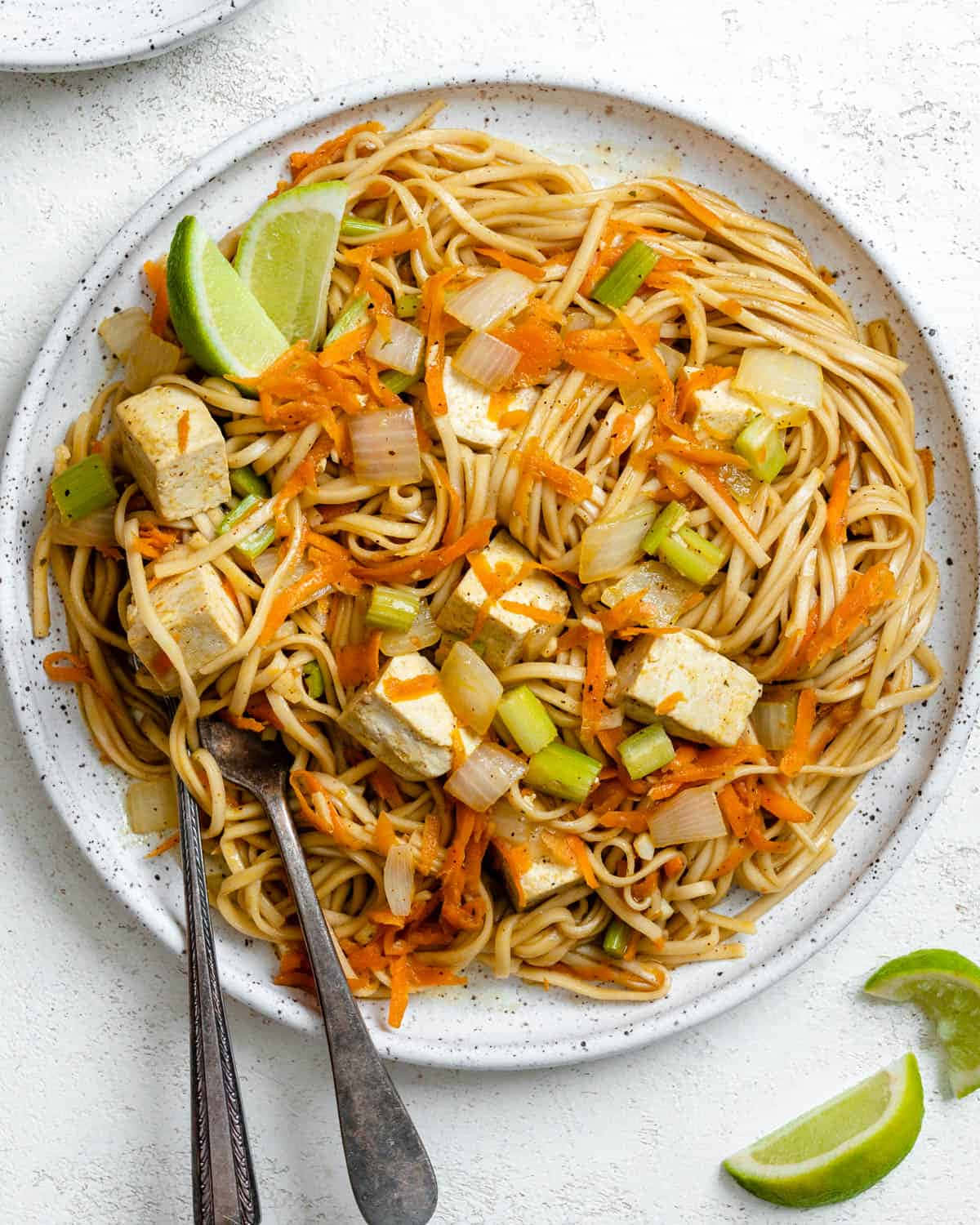 Noodles 桌布 壁紙 — 一個有斑點的白色盤子盛裝著色彩鮮豔的炒麵，搭配豆腐、紅蘿蔔、青蔥和萊姆角。