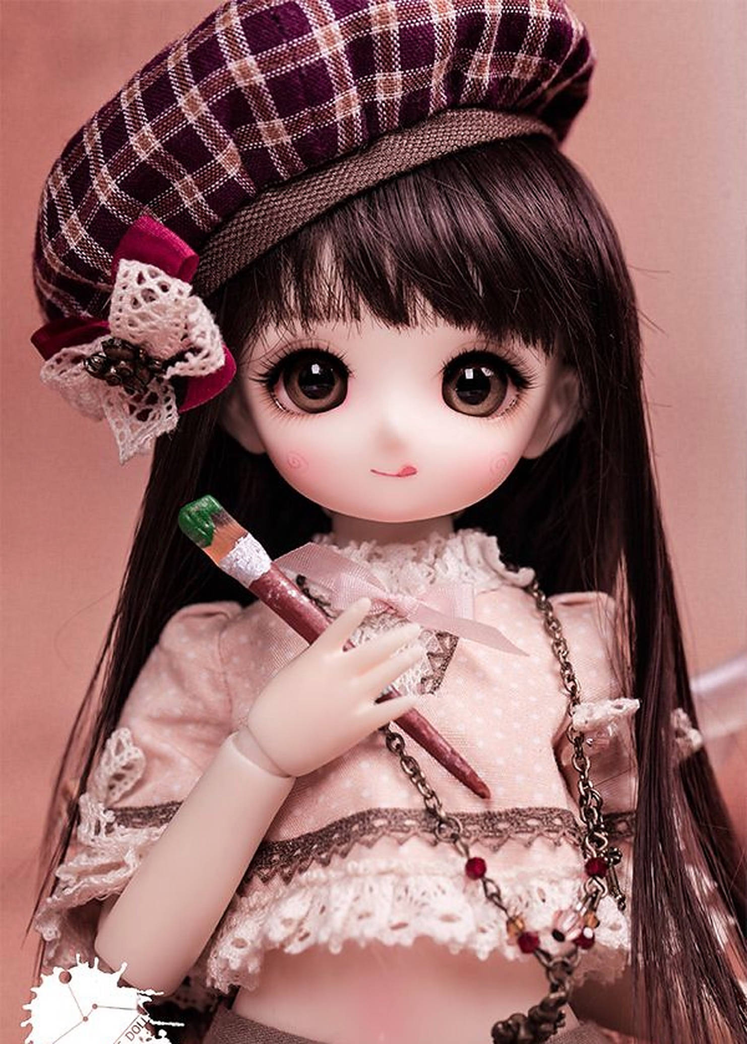 Doll 桌布 壁紙 — 一個有棕色大眼的娃娃戴著格紋貝雷帽，在柔和粉紅色背景前拿著畫筆。