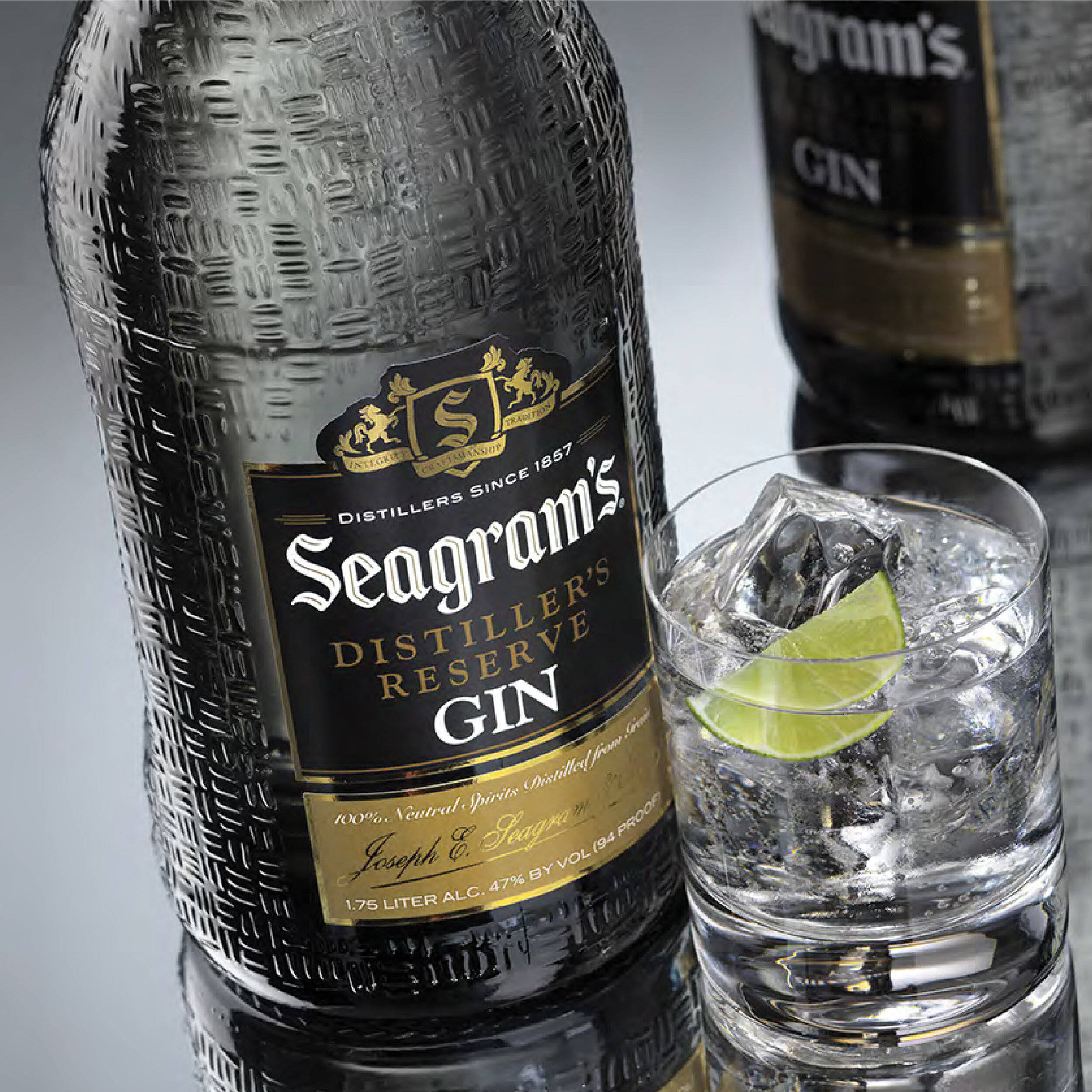 高清 桌布 壁紙 — 一個有紋理的 Seagram's 琴酒瓶立在一個裝滿冰塊和萊姆角的 rocks 杯旁邊。