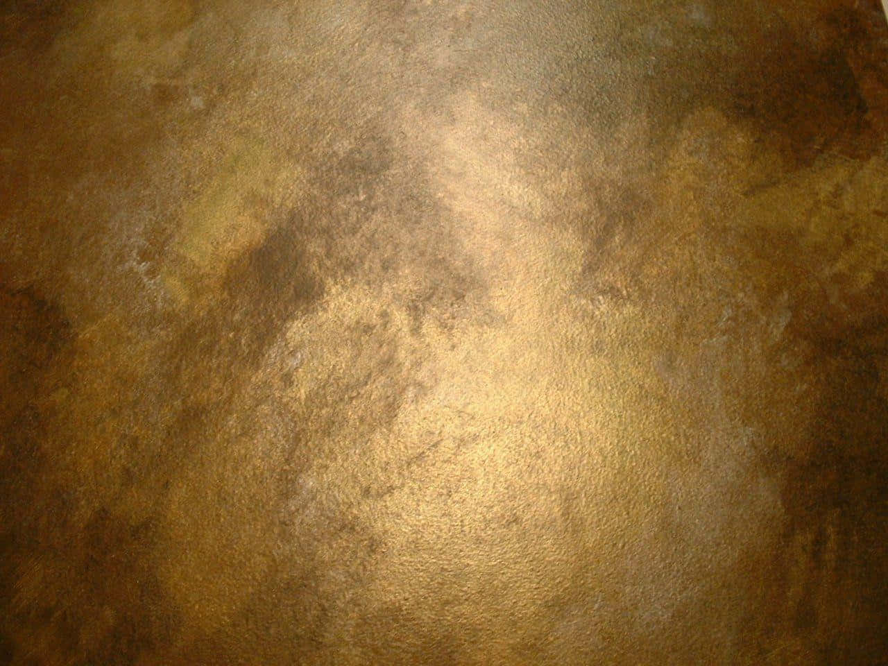 Bronze 桌布 壁紙 — 一個有紋理的金屬金色表面的特寫，帶有斑駁的棕色和古銅色調，反射柔和光線。