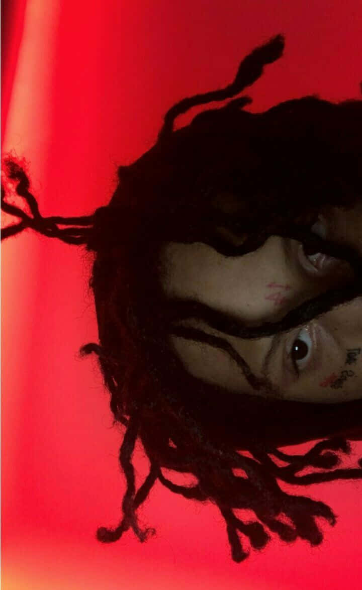 Trippie Redd 桌布 壁紙 — 一個有辮子頭和刺青的人的特寫，背景是鮮豔的紅色。
