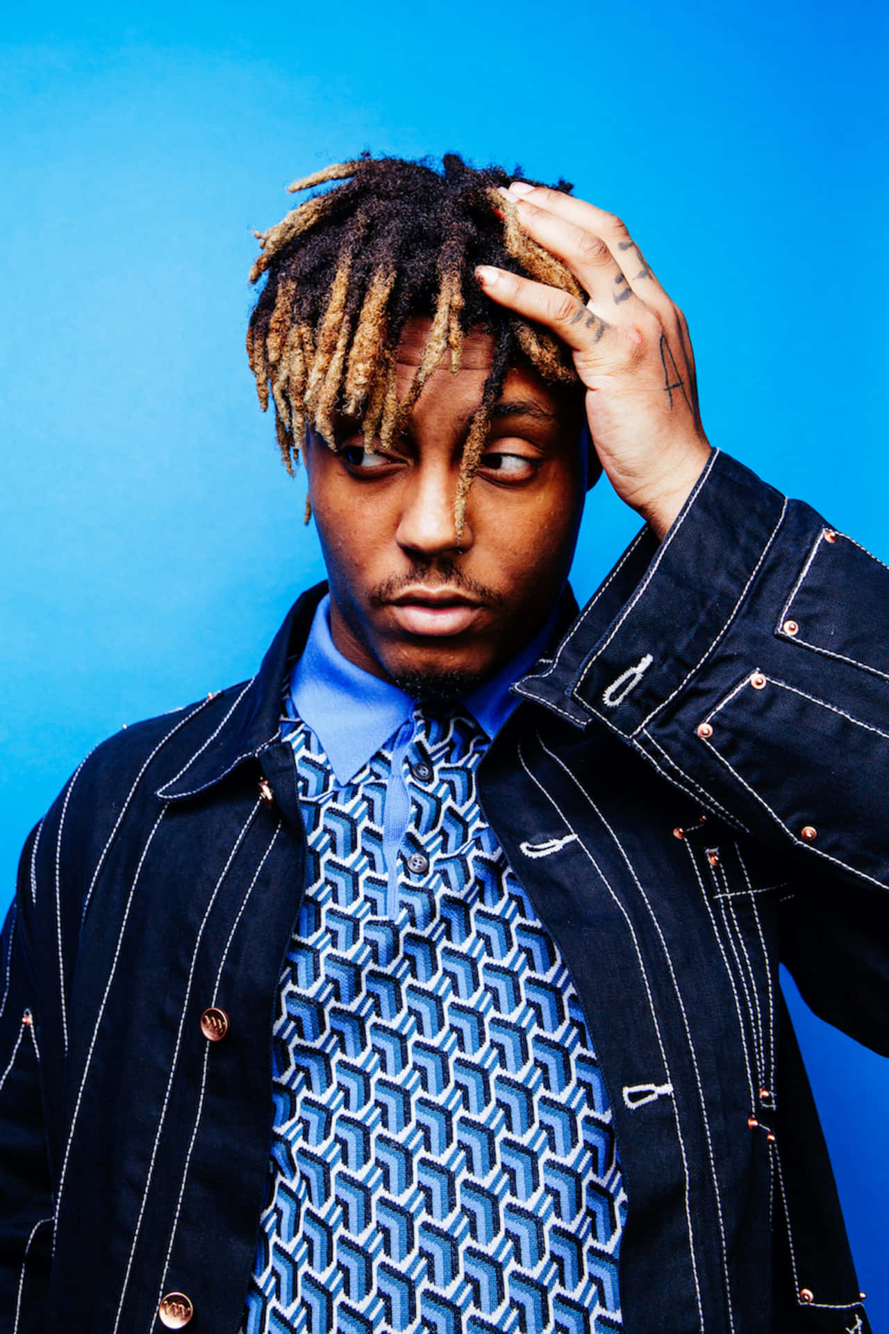 有辮子頭和刺青的男人在工作室肖像中觸摸頭部。 — Juice Wrld 壁紙