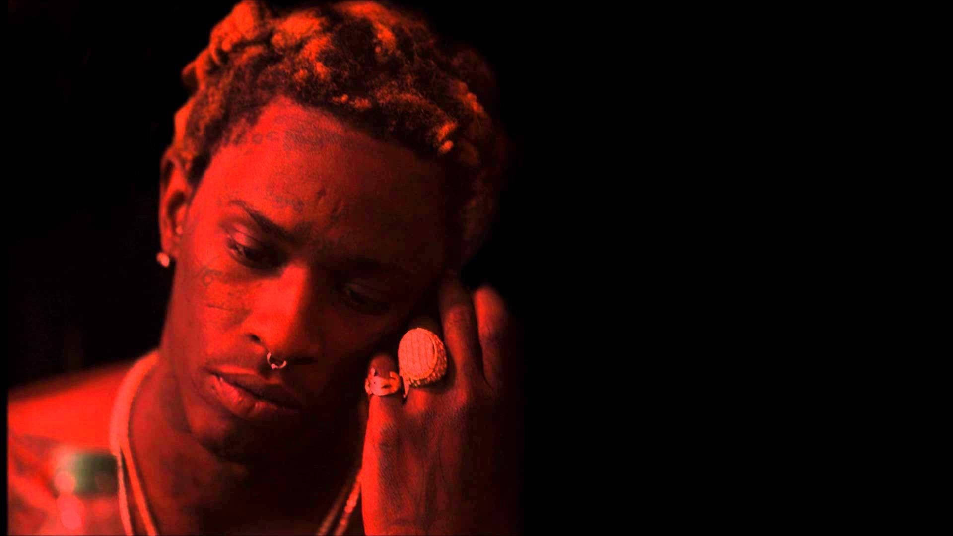 Thug 桌布 壁紙 — 一個有辮子頭髮和面部穿孔的人，在黑色背景下沐浴在強烈的紅光中，手放在臉附近。