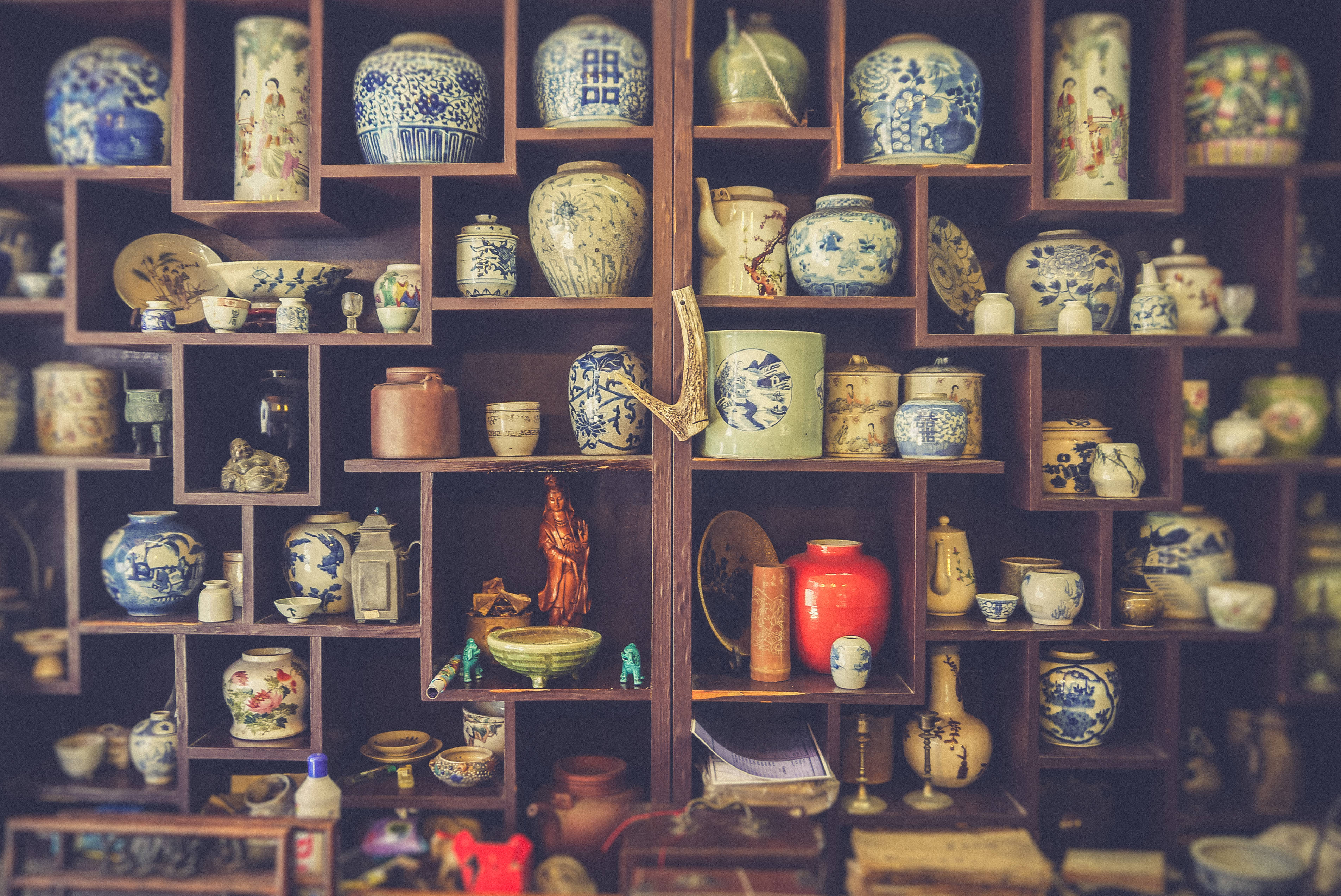 Shelves 桌布 壁紙 — 一個木架展示了一系列豐富的復古陶瓷盆、碗和雕像，採用藍色、白色和大地色調。