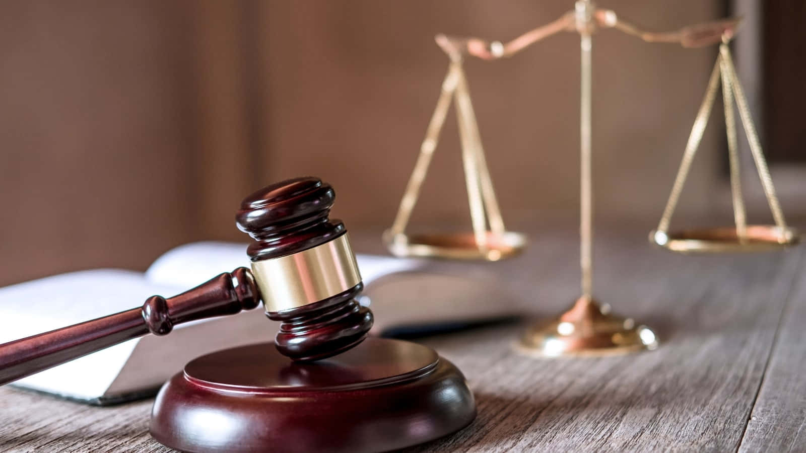 Justice 桌布 壁紙 — 一個木槌放在其支架上，旁邊有一個金色的正義天秤和一本打開的書，放在質樸的木桌上。