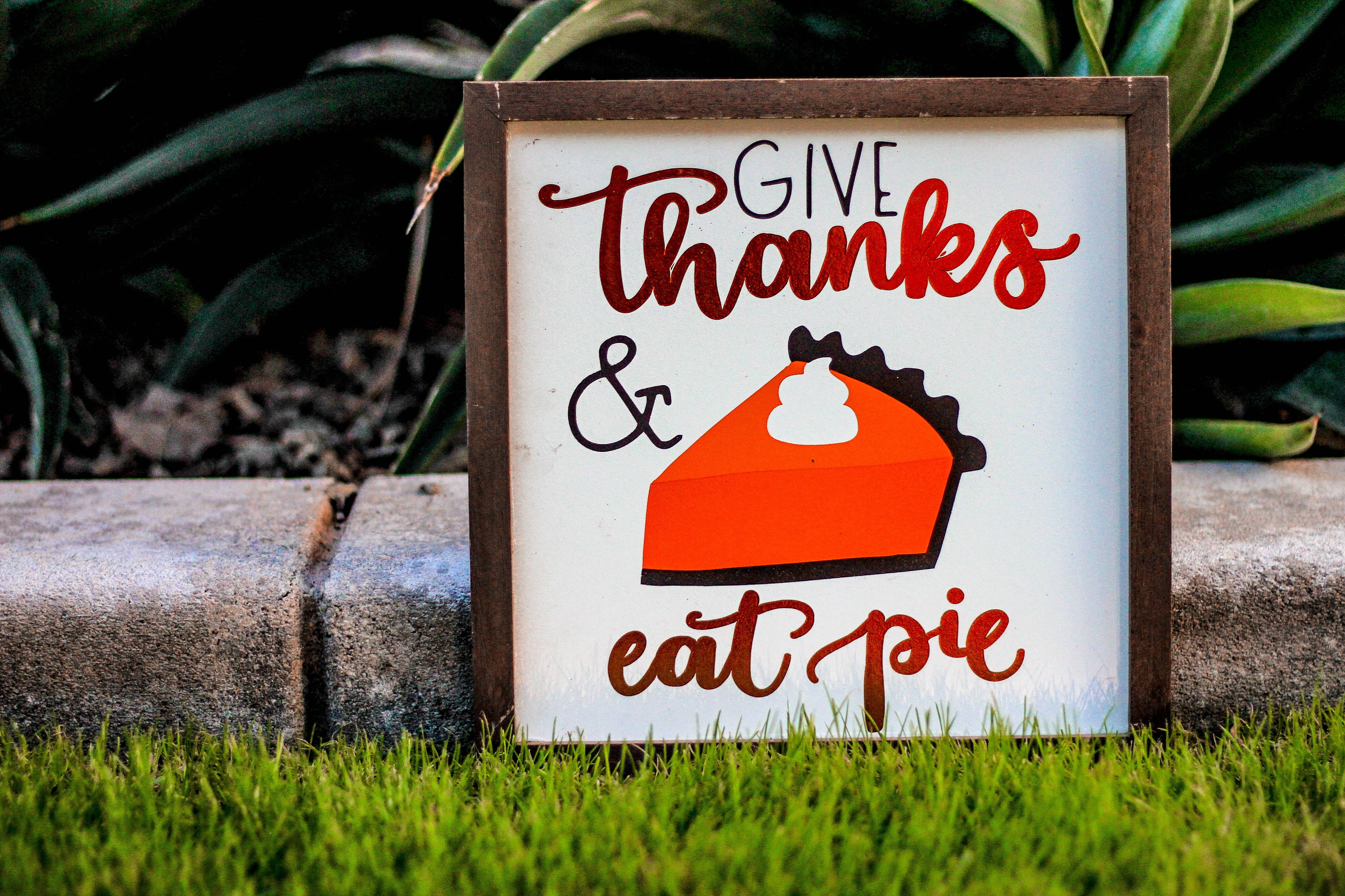 Happy Thanksgiving 桌布 壁紙 — 一個木牌寫著「Give Thanks & Eat Pie」，並有餡餅插圖，放在石階旁的草地上。