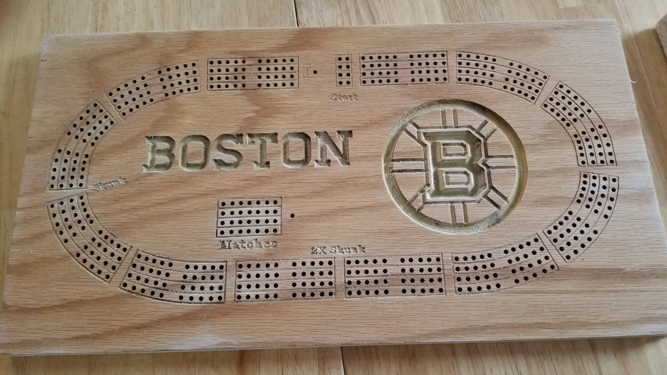 Board Game 桌布 壁紙 — 一個木製克里比奇棋盤，刻有「BOSTON」和棕熊隊標誌，放置在淺色木質表面上。