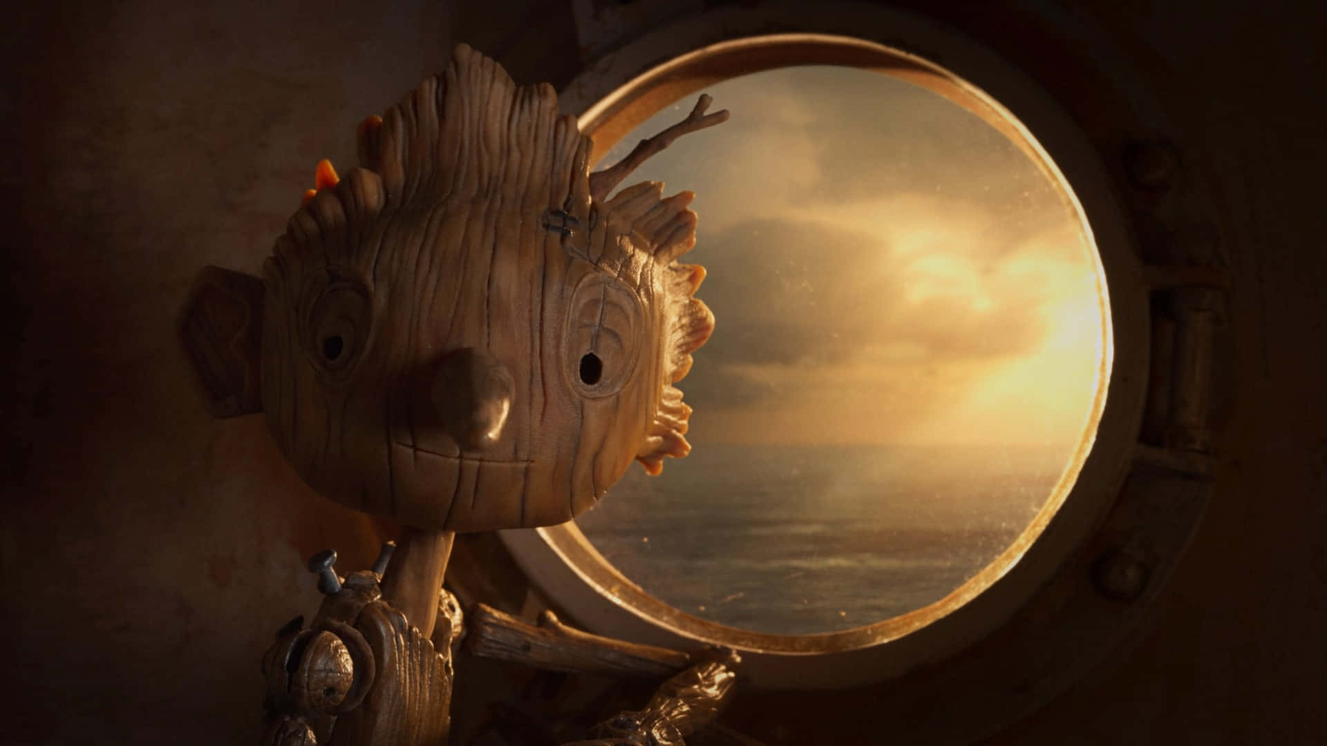 Guillermo Del Toro's Pinocchio 桌布 壁紙 — 一個木製動畫角色從船艙舷窗凝視著海洋上金色的日落。