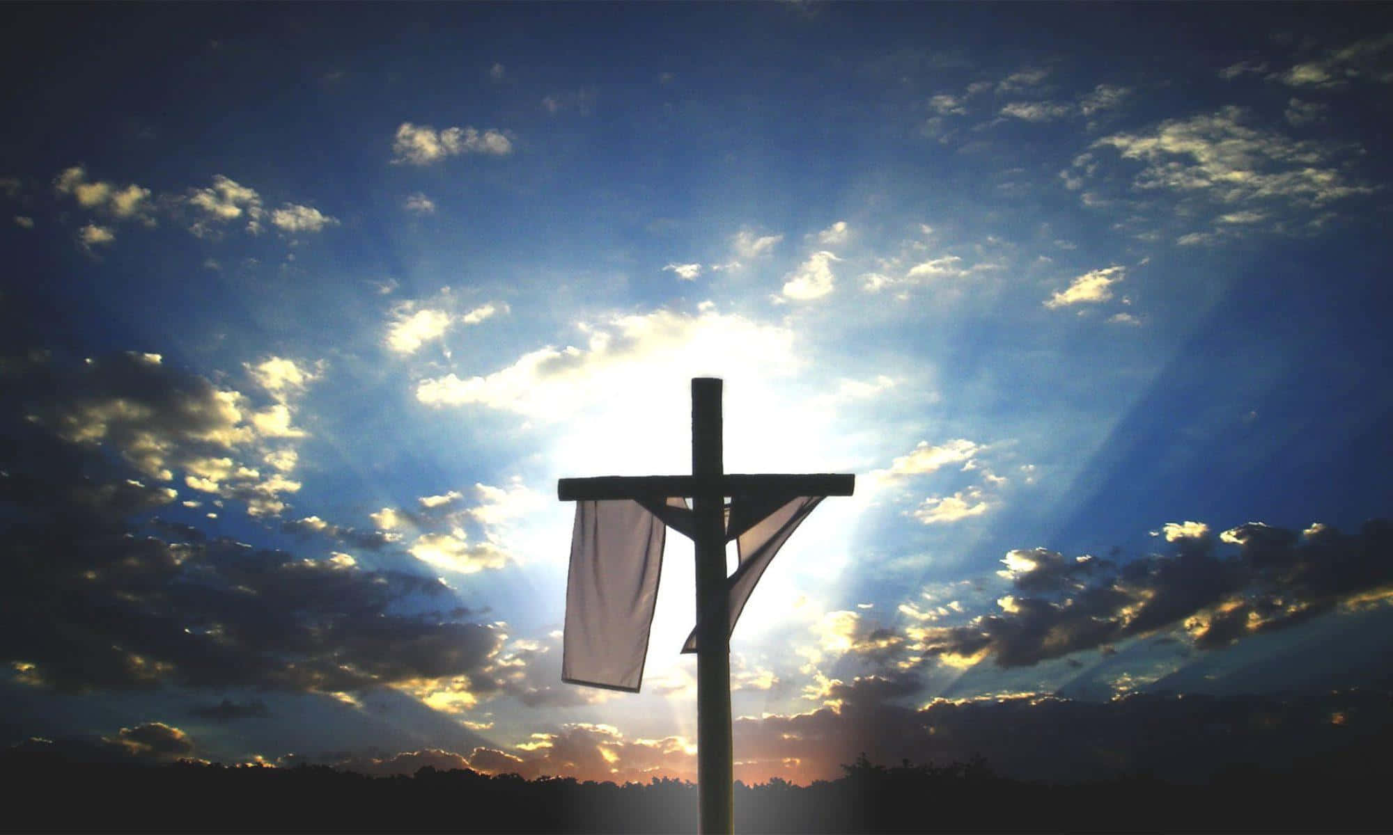神 桌布 壁紙 — 一個木製十字架在日落時分剪影在戲劇性的天空，陽光穿透金色雲層。