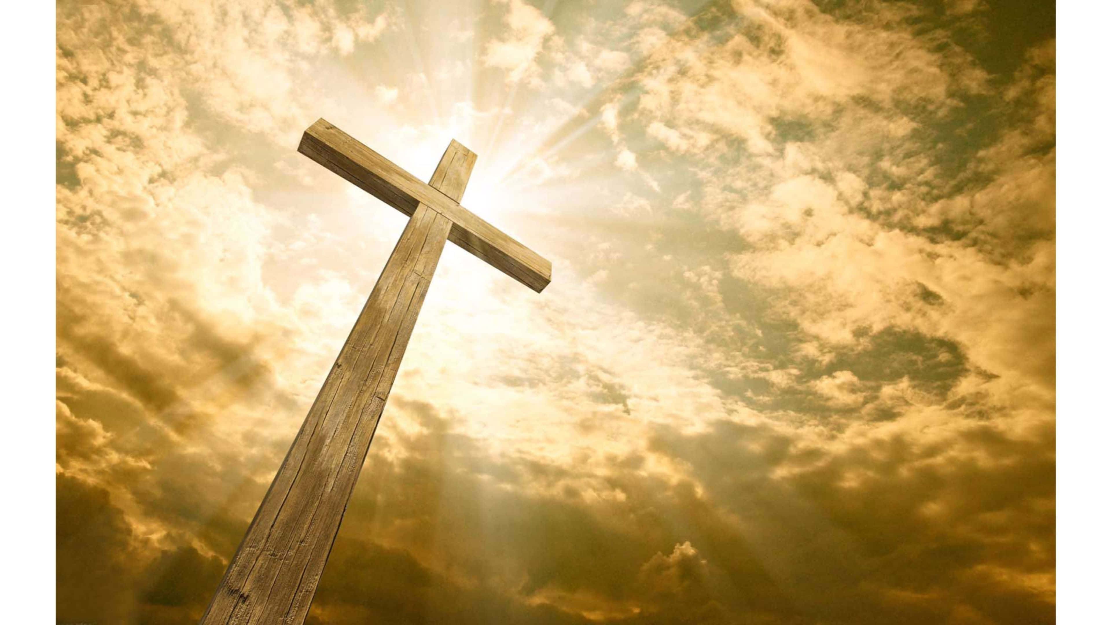 Religious Easter 桌布 壁紙 — 一個木製十字架在金色天空下高高聳立，燦爛的陽光穿透戲劇性的雲層。