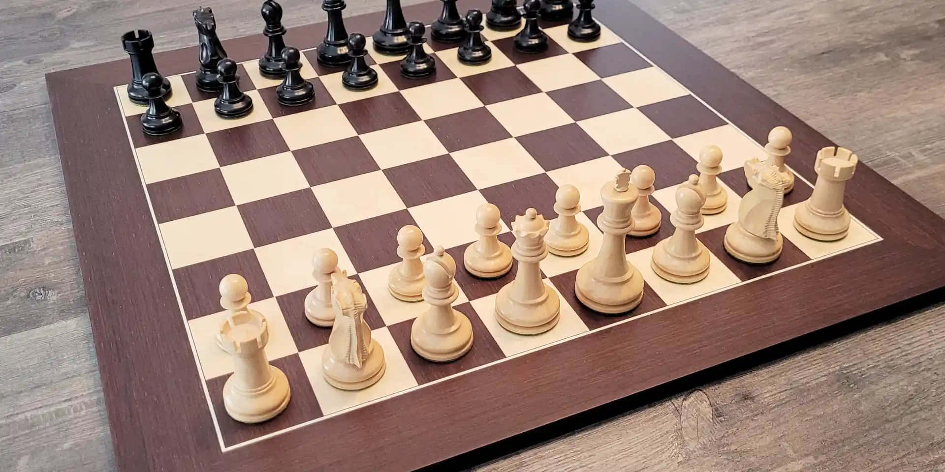 Chessboard 桌布 壁紙 — 一個木製棋盤，上面擺放著白色和黑色的棋子準備對弈，擱在灰色木地板上。