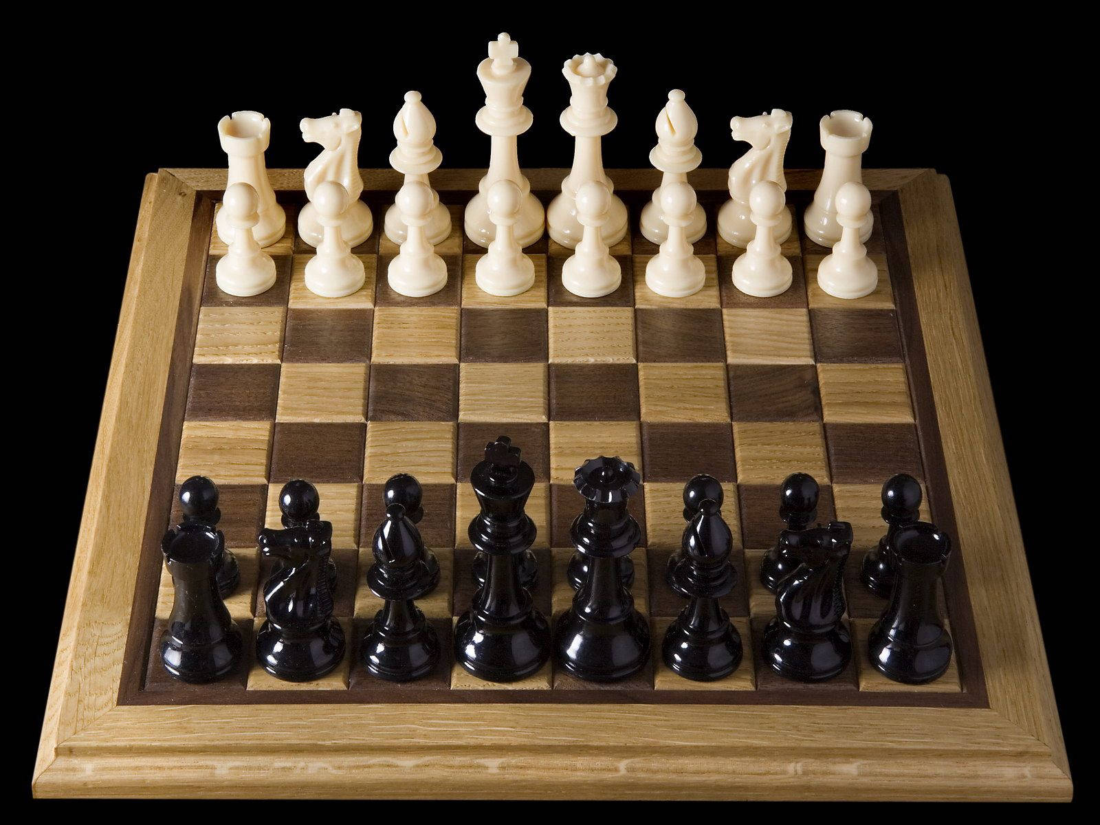 Party 桌布 壁紙 — 一個木製棋盤，黑白棋子排列整齊，準備在純黑背景下對弈。