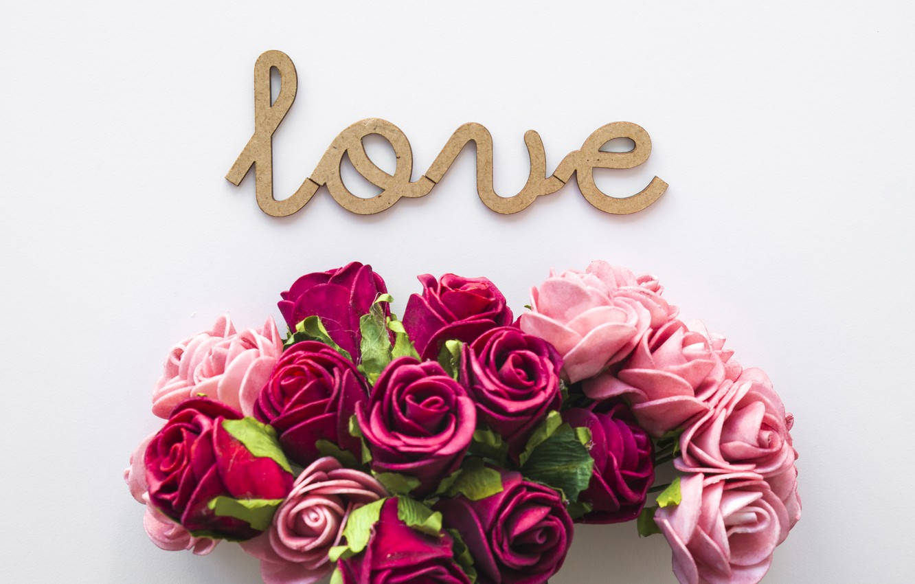 Romantic Love Flowers 桌布 壁紙 — 一個木製的「love」標誌放在一束鮮豔的粉紅色和洋紅色玫瑰上方，背景是潔淨的白色。