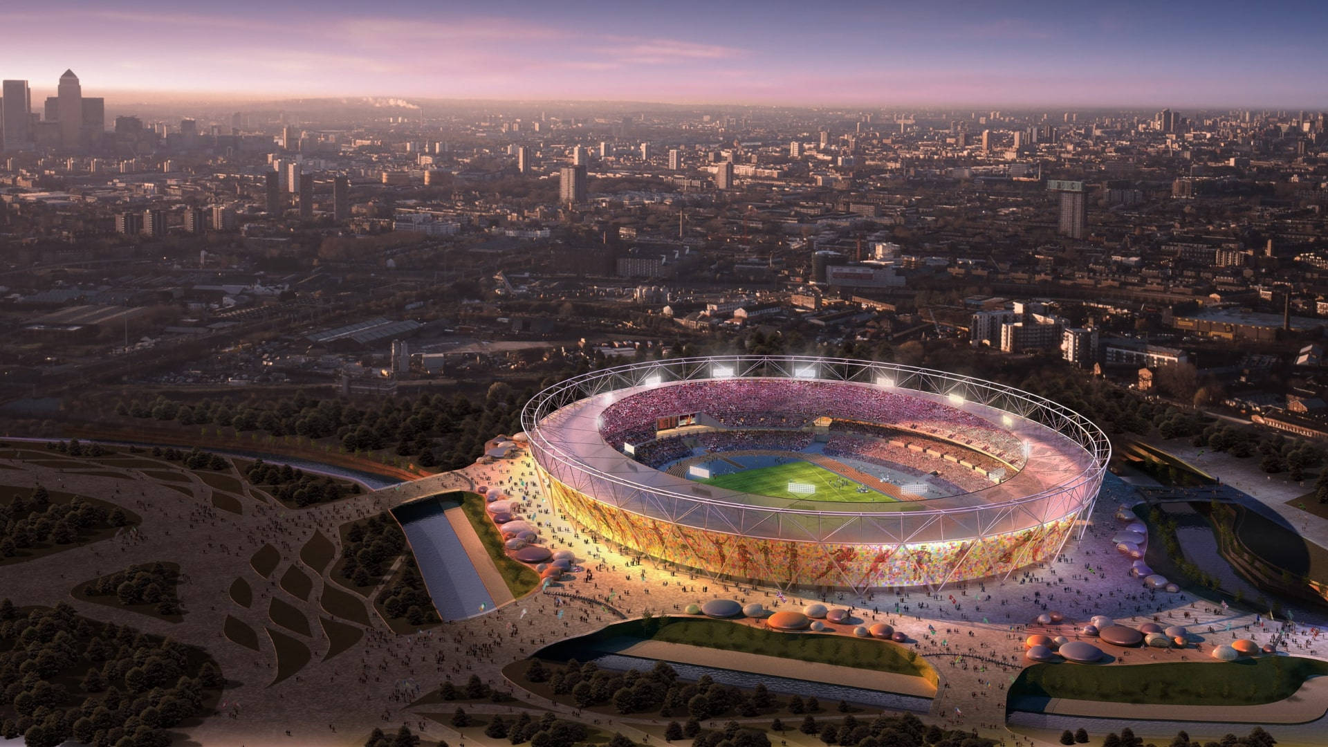 Olympics 桌布 壁紙 — 一個未來主義的體育場在黃昏時分閃爍著鮮豔的燈光，周圍是廣闊的城市景觀和茂密的綠植。