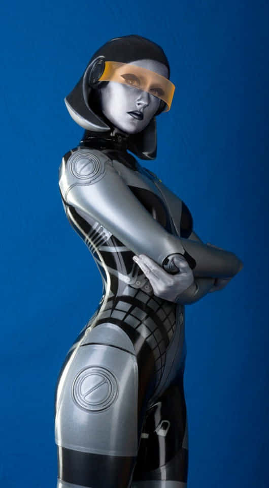 Mass Effect Edi 桌布 壁紙 — 一個未來感十足的女性機器人，身穿流線型銀黑色裝甲，自信地站在純藍色背景前。