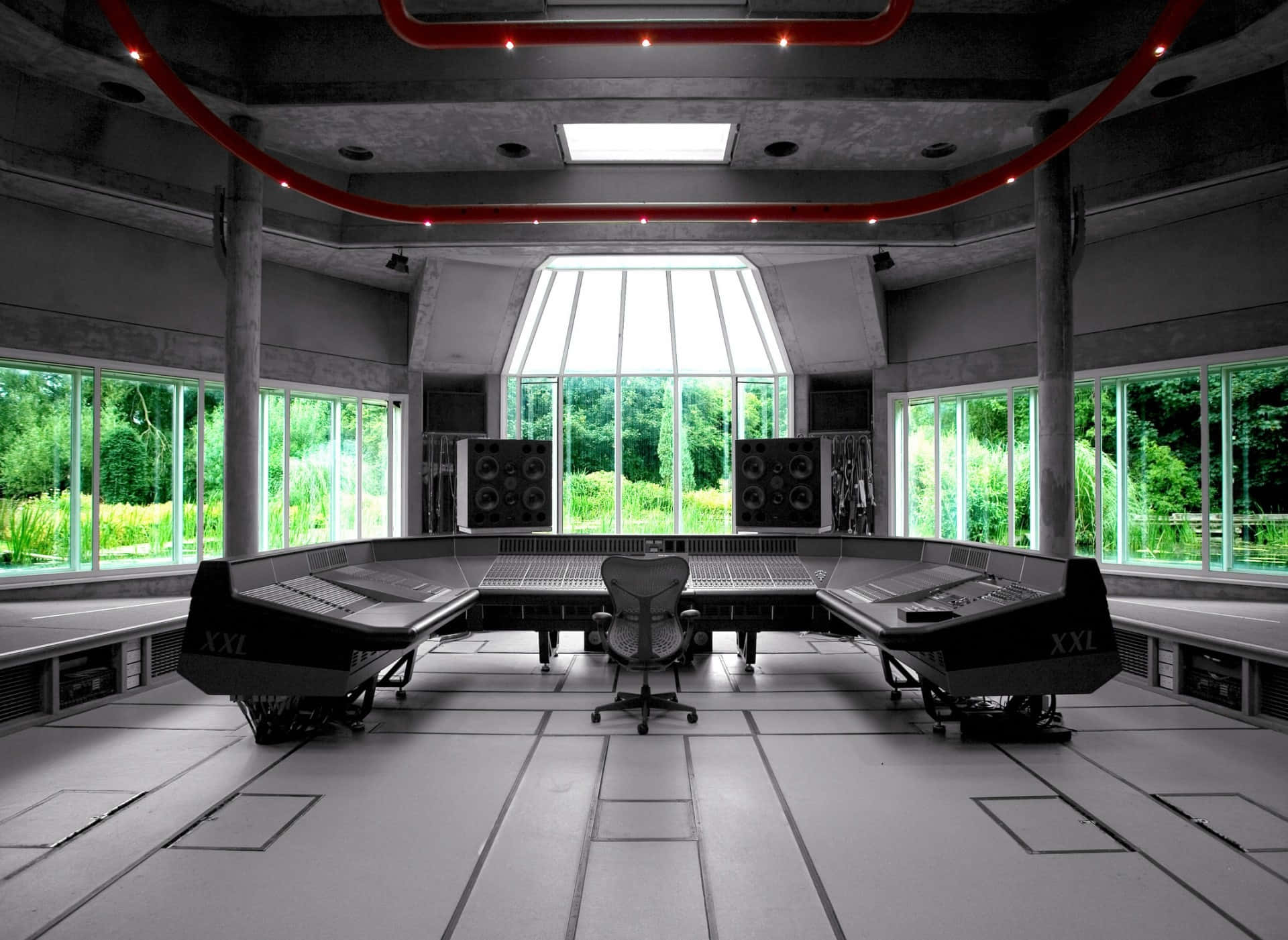 Studio 桌布 壁紙 — 一個未來風格的混凝土錄音室，配有紅色霓虹管和大窗戶，可欣賞茂密的綠植。