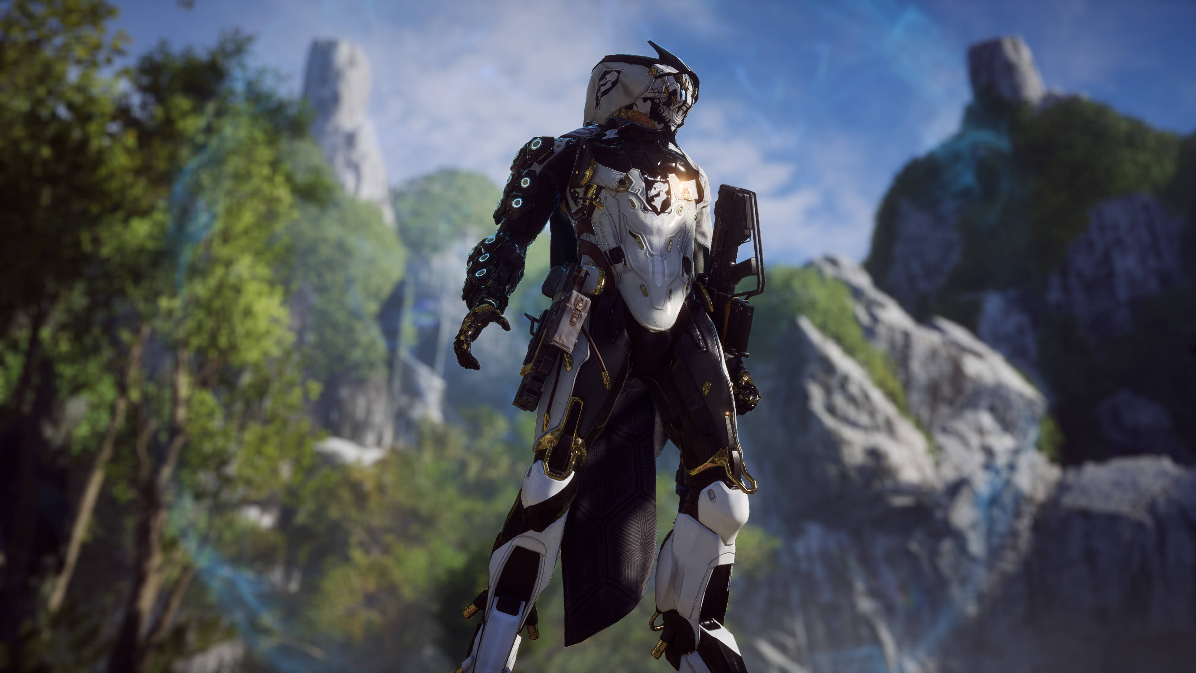 anthem 4K 桌布 壁紙 — 一個未來風格的裝甲戰士站在一個茂密的山谷中，周圍有高聳的岩石 formations 和鮮豔的綠色植物，在明亮的藍天下。
