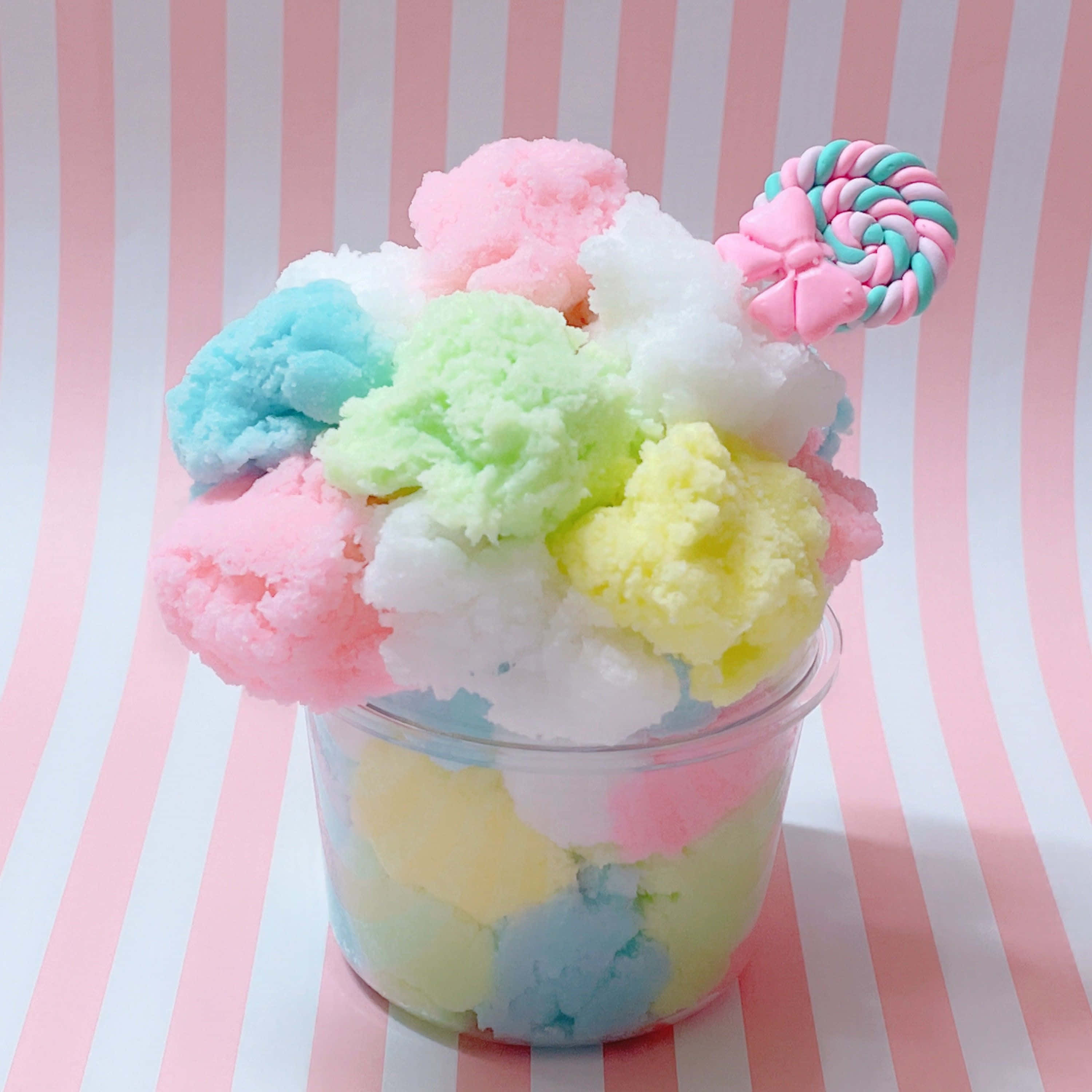 slime 桌布 壁紙 — 一個杯子溢出粉彩色柔軟雪狀物質，上面有粉紅色和藍綠色的棒棒糖。