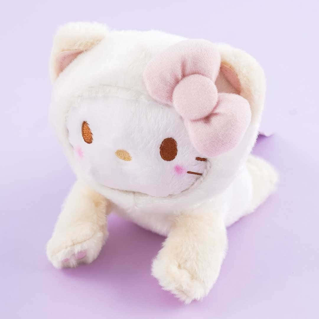 Kawaii Hello Kitty 桌布 壁紙 — 一個柔軟的白色Hello Kitty毛絨玩具，帶有粉紅色蝴蝶結，蜷縮在粉紫色背景上。