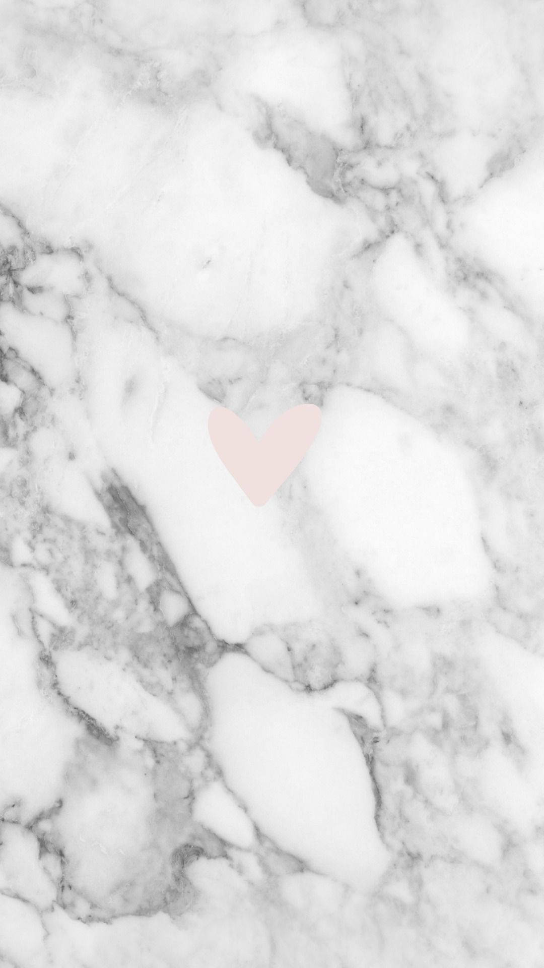 Pink Heart 桌布 壁紙 — 一個柔軟的粉紅色心形輕輕放在帶有流動紋理的白色和灰色大理石表面上。