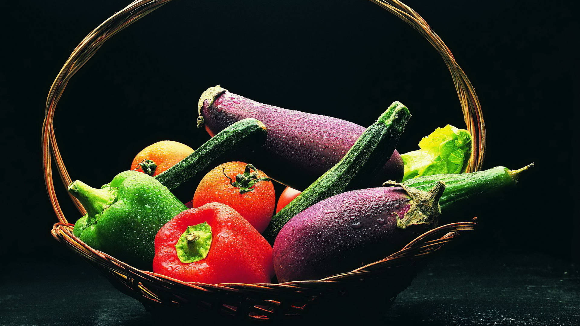 Vegetable 桌布 壁紙 — 一個柳條籃子裝滿了色彩鮮豔的新鮮蔬菜，如茄子、櫛瓜、番茄和甜椒，在深色背景下閃爍著水珠。