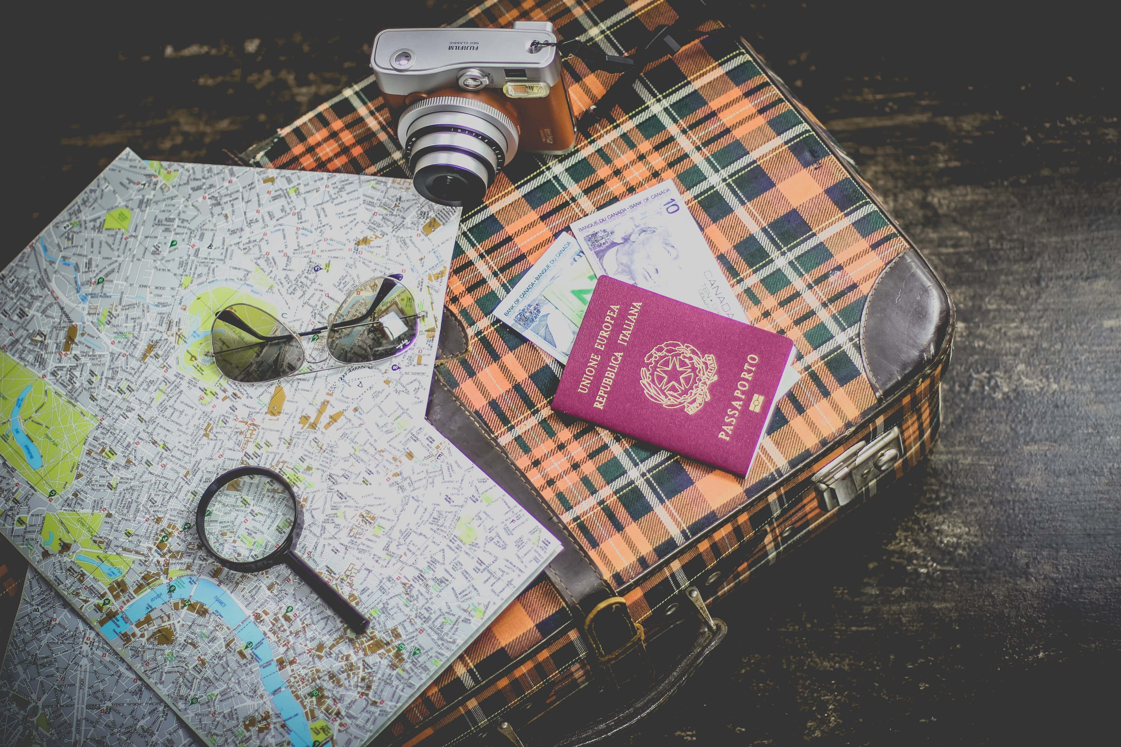 Passport 桌布 壁紙 — 一個格紋布料的復古行李箱內有護照、放大鏡、地圖和相機，準備好去旅行。