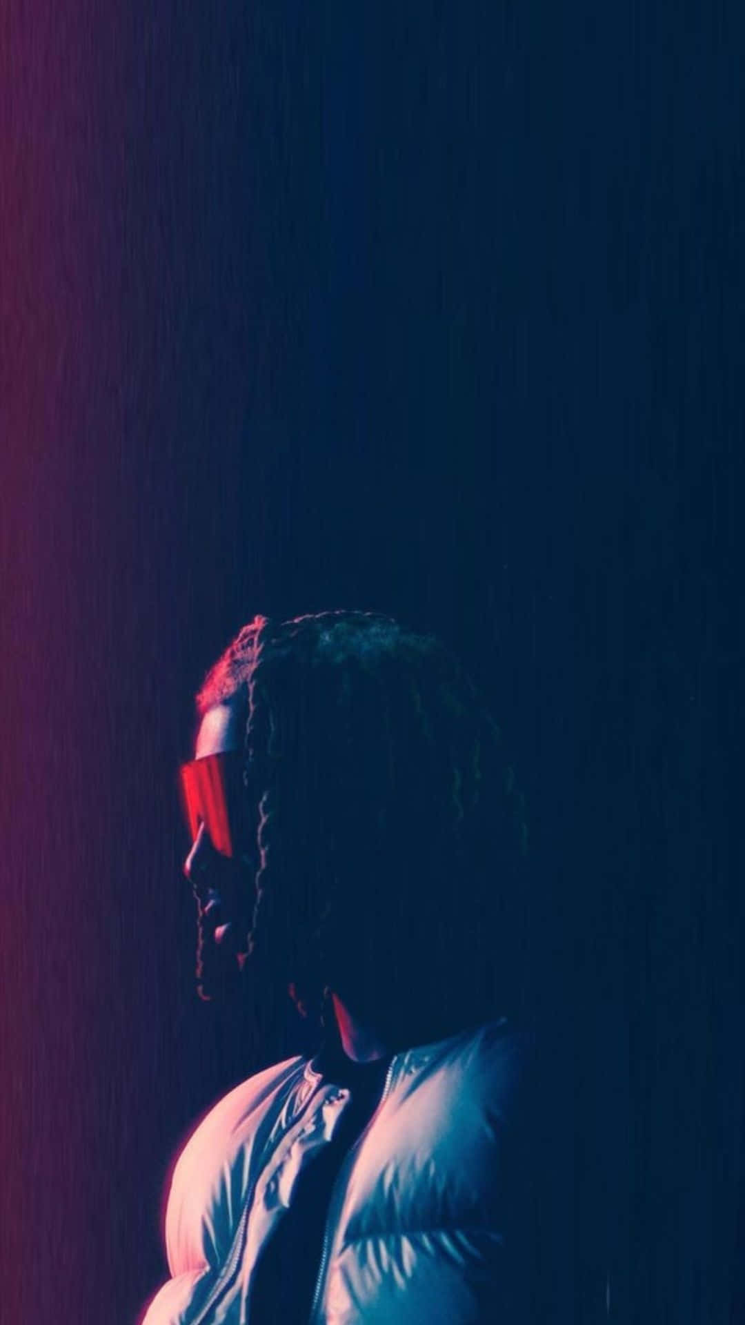 Playboi Carti 桌布 壁紙 — 一個梳著辮子、戴著紅色太陽眼鏡的人站在雨中，霓虹燈投射出藍色和紫色的色調。