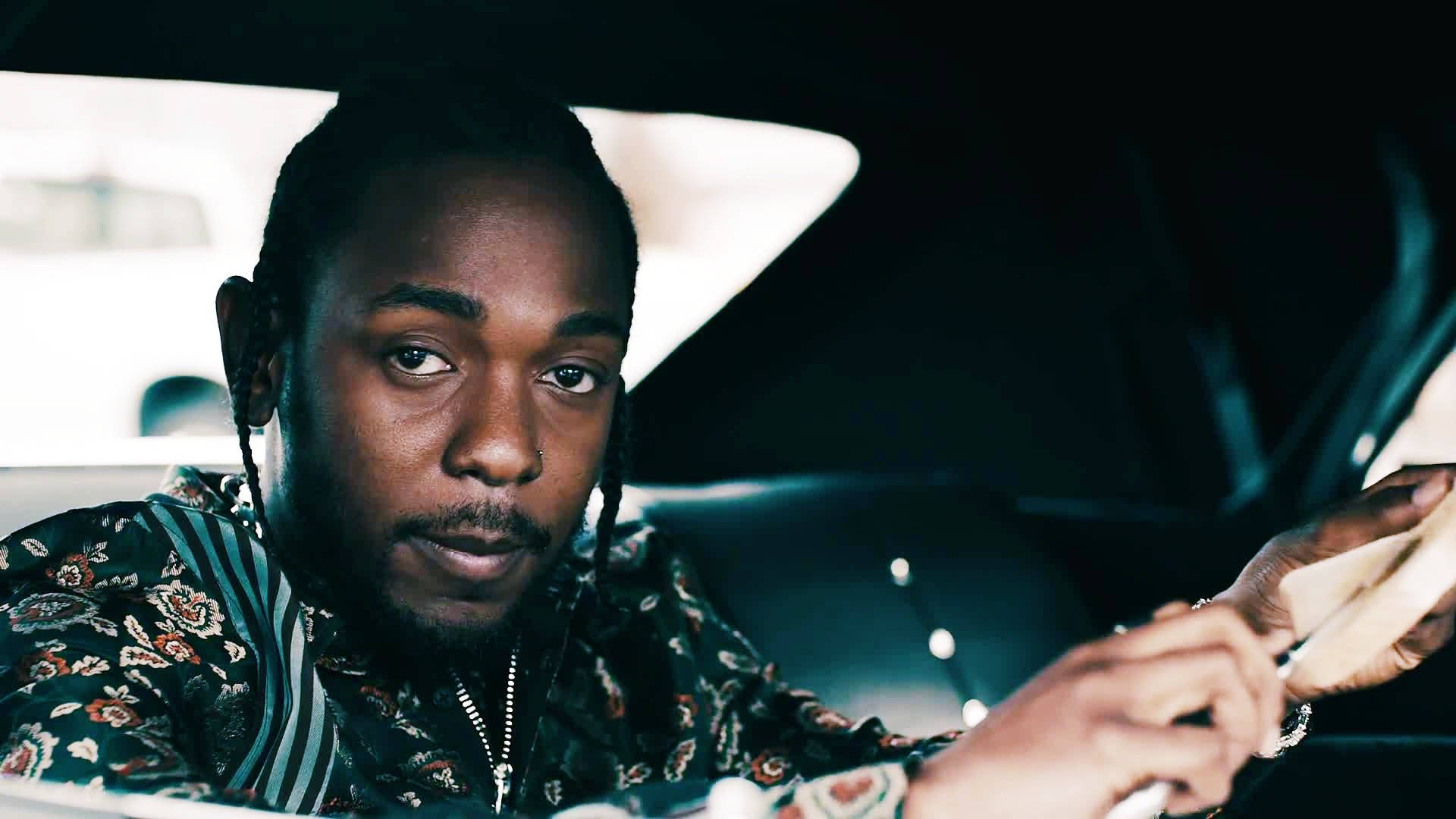 Kendrick Lamar 桌布 壁紙 — 一個梳辮子、戴鼻環的男人晚上坐在車裡，表情嚴肅地看著手機。