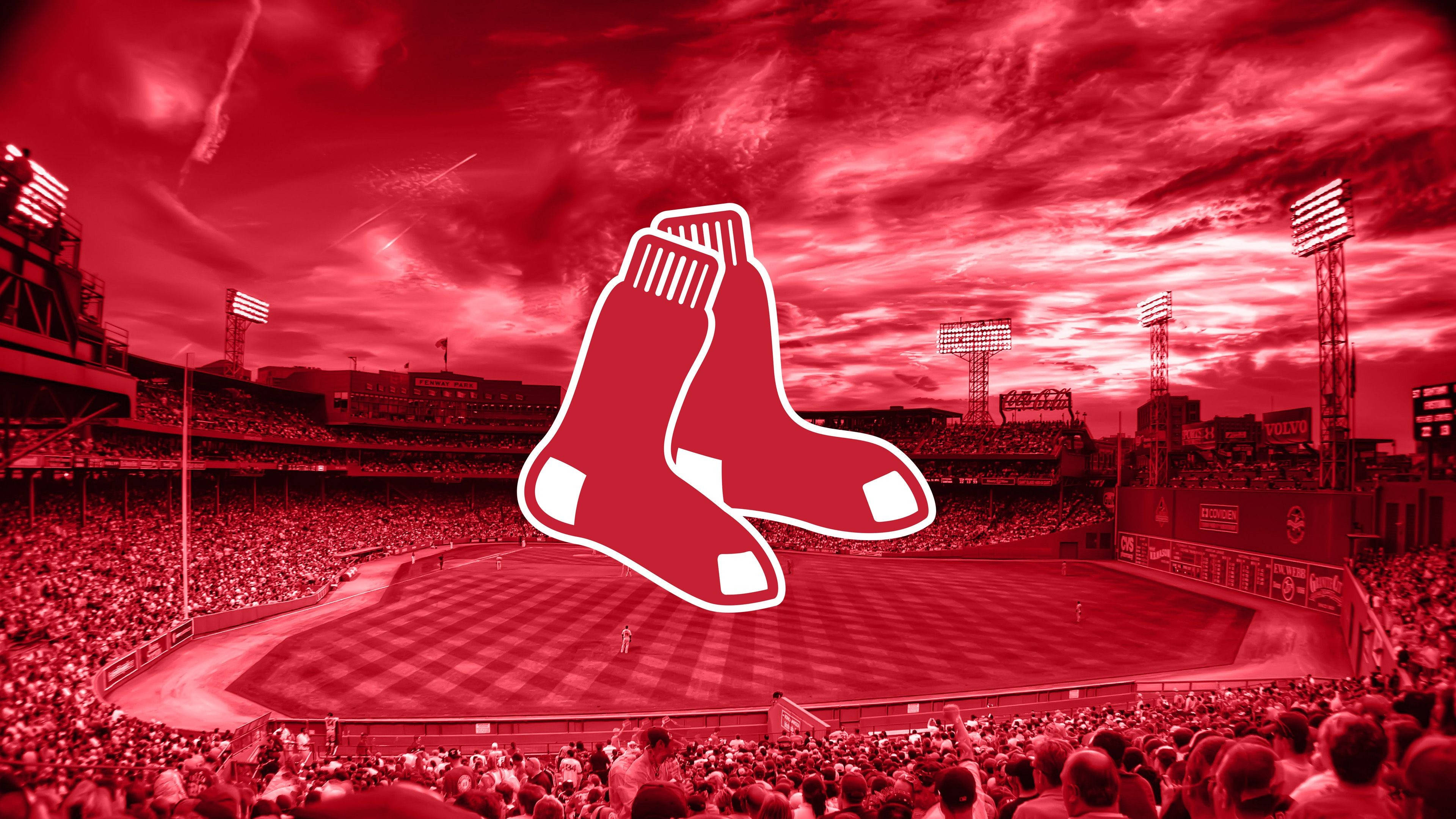 Red Sox 桌布 壁紙 — 一個棒球場在戲劇性的日落天空下沐浴在紅光中，並突出疊加了波士頓紅襪隊的標誌。