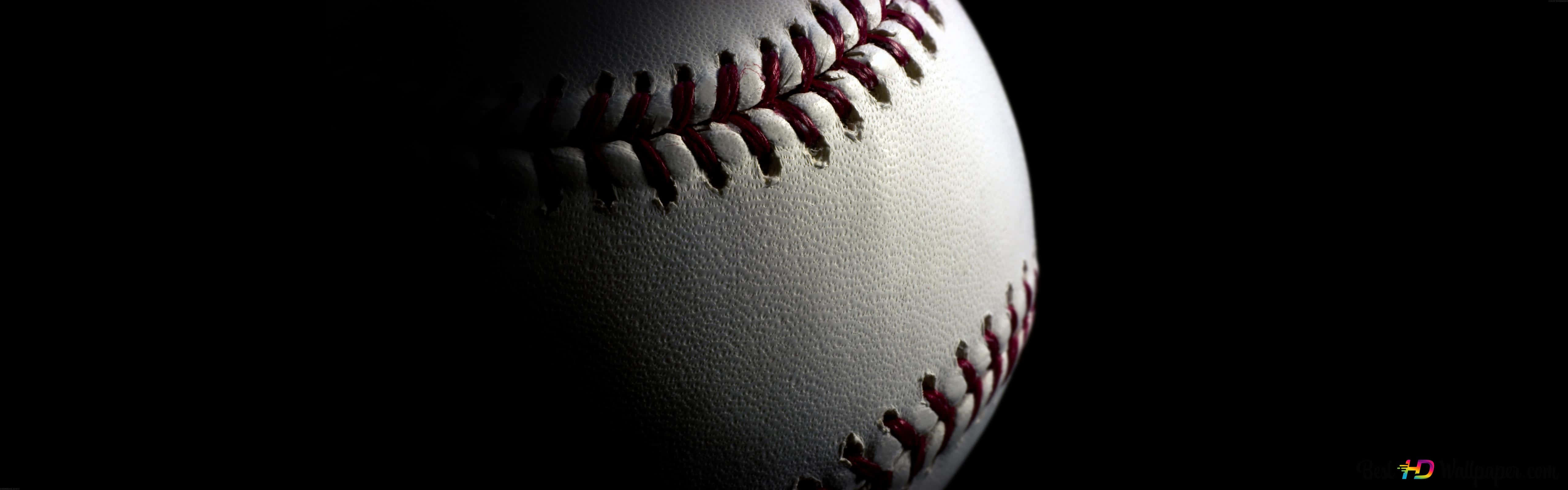 Awesome Baseball 桌布 壁紙 — 一個棒球的特寫，紅色縫線在黑色背景上被戲劇性的燈光突出顯示。