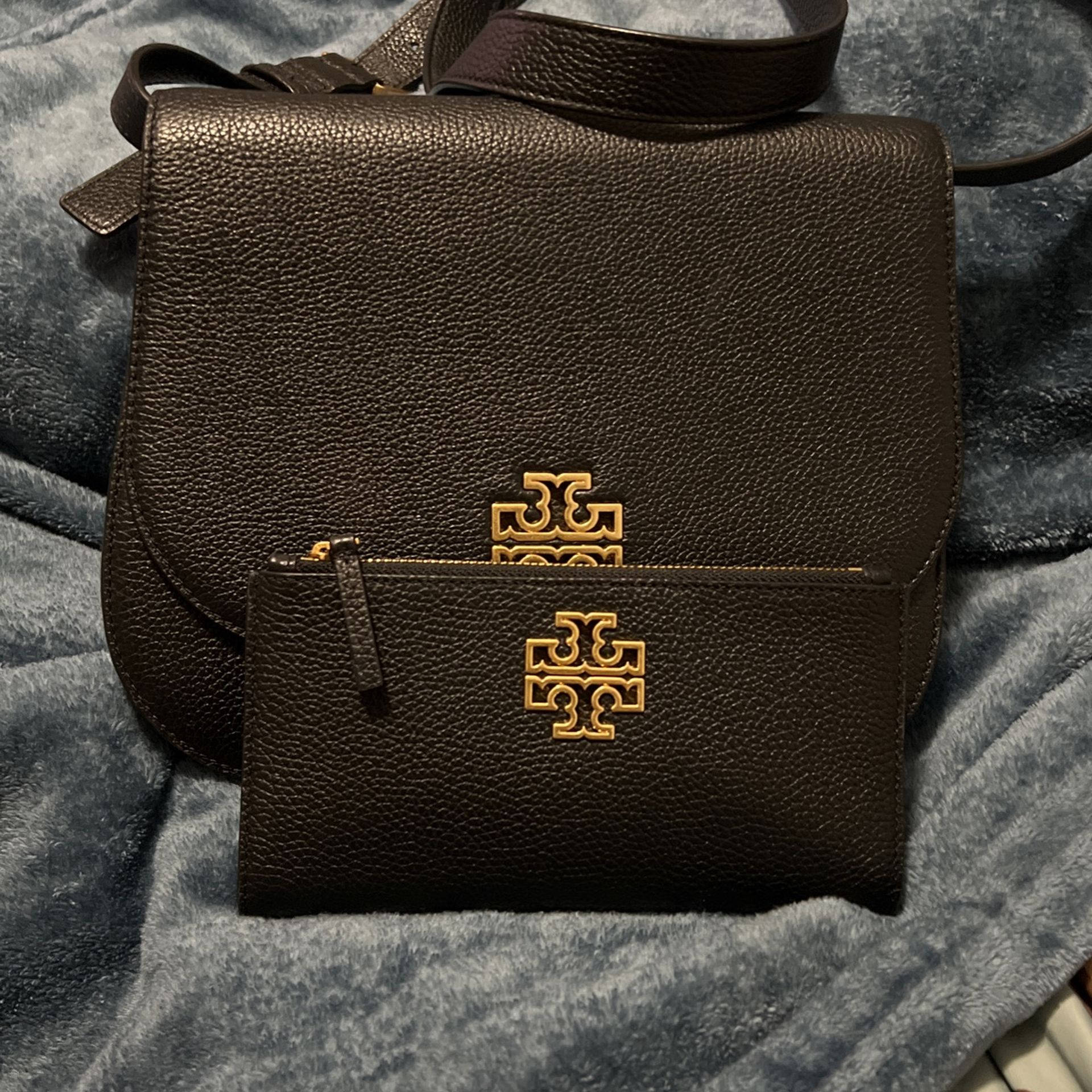 Tory Burch 桌布 壁紙 — 一個棕色紋理皮革Tory Burch手提包及配套金色標誌錢包放在柔軟的藍色毛毯上。