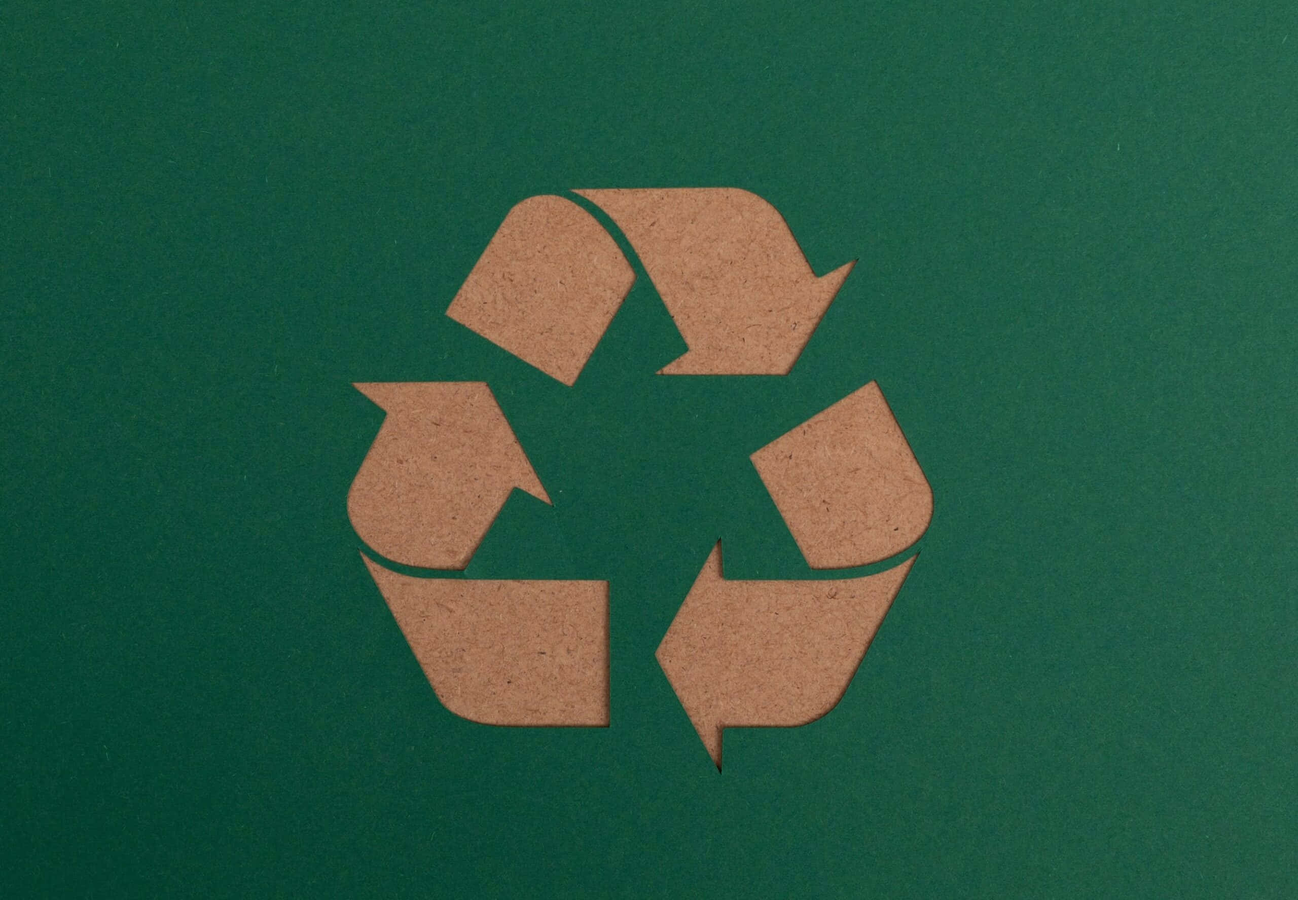 waste 桌布 壁紙 — 一個棕色紙板回收標誌剪影，置於有紋理的深綠色背景中央。